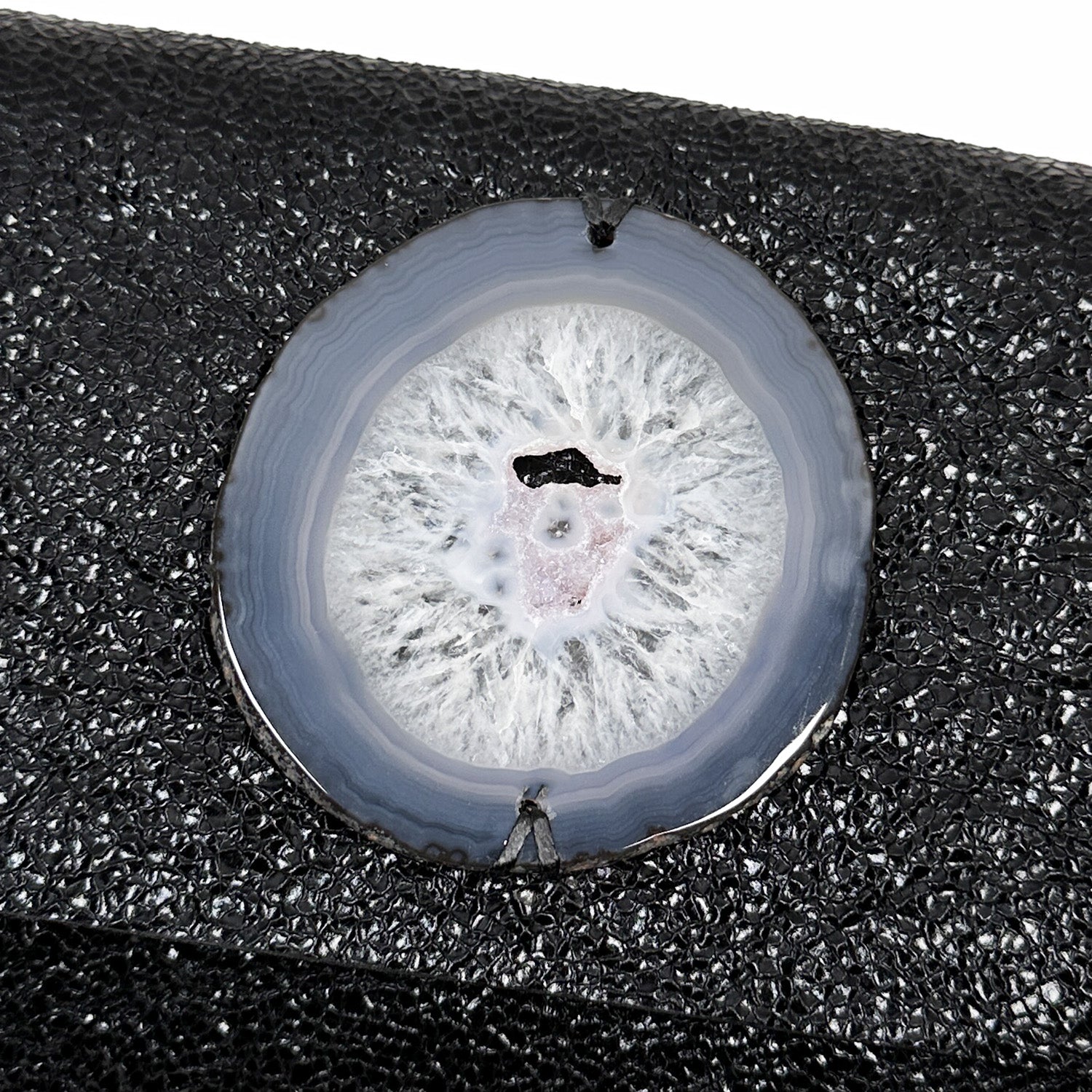 The BAGUETTE by Evoke Women – a sleek handbag crafted from textured black Italian leather, featuring a bold gunmetal chain strap and a round agate centerpiece, elegantly displayed on a white background.