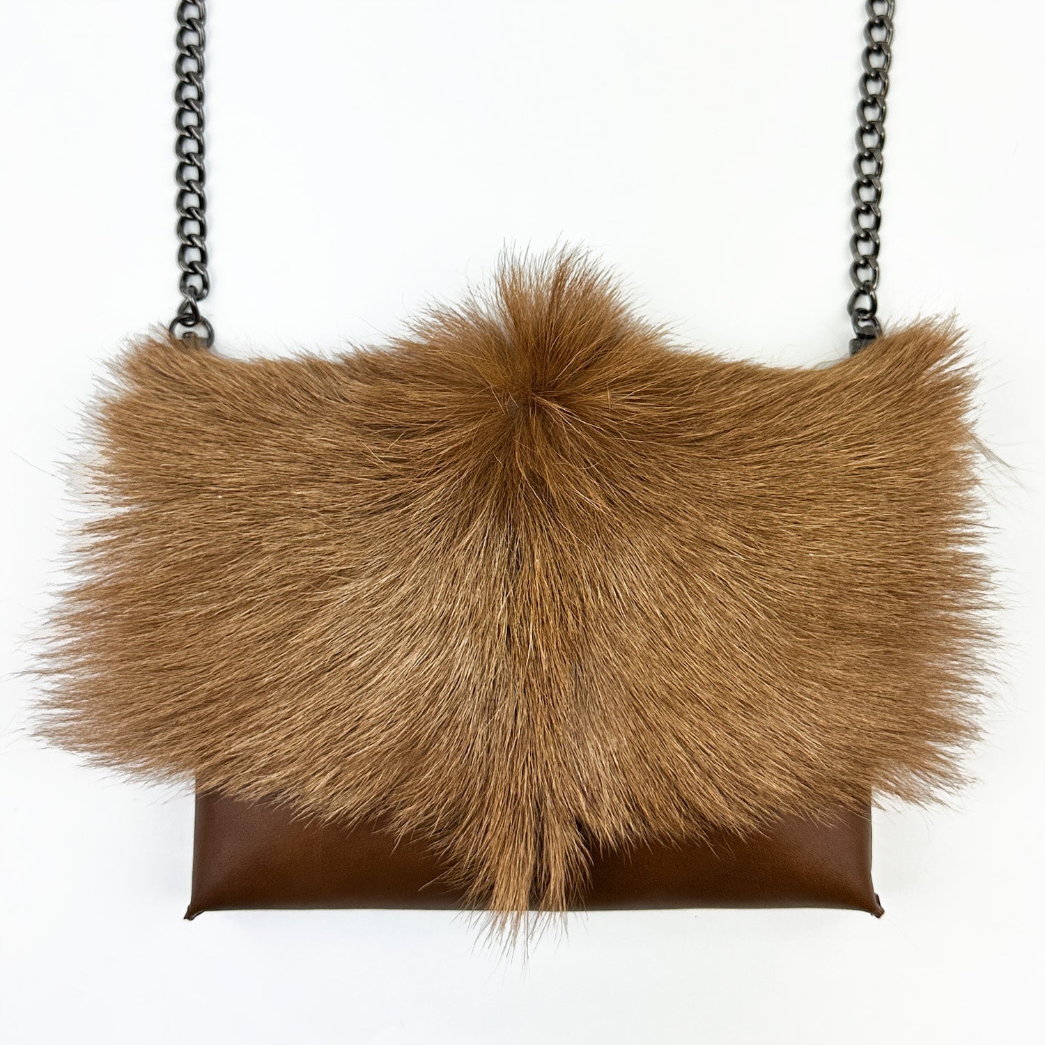 Presenting the BAHAMA FUR - COGNAC by evokewomen: a brown, furry crossbody purse featuring a chain strap and a fluffy flap, showcased against a plain white background.