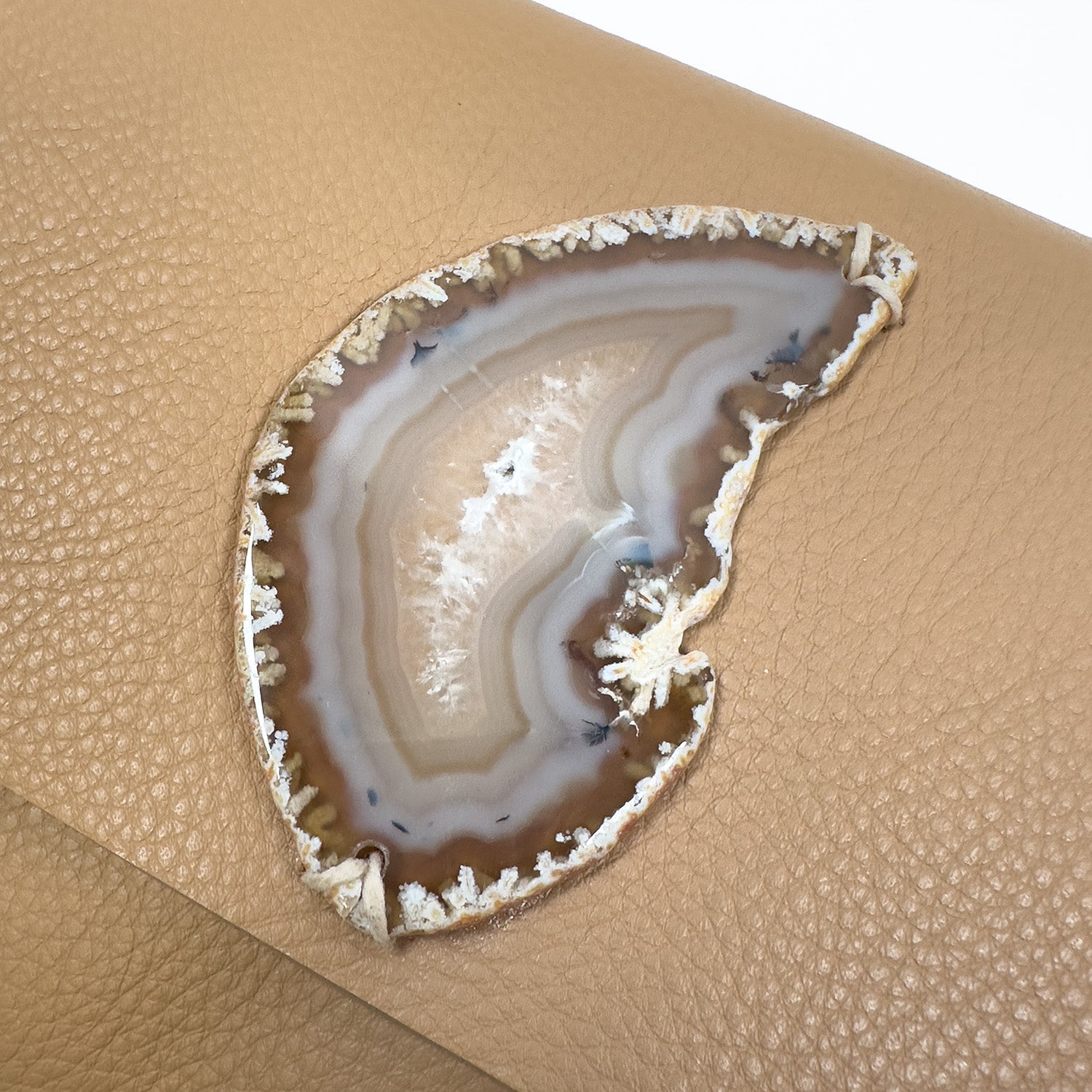 Close-up of the BAHAMA - CAMEL - knotted strap by evokewomen, featuring a tan Italian leather surface with a polished agate slice embedded.