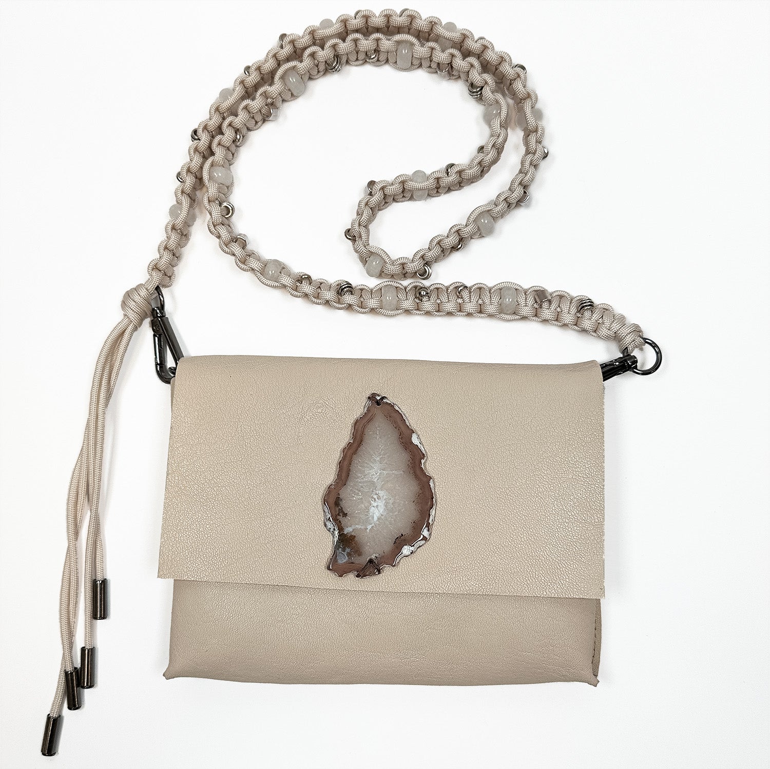 Introducing the BAHAMA by evokewomen—a sophisticated cross body bag crafted from luxurious Italian leather in a refined almond hue. It features a signature agate slice on the front flap and a distinct knotted shoulder strap.