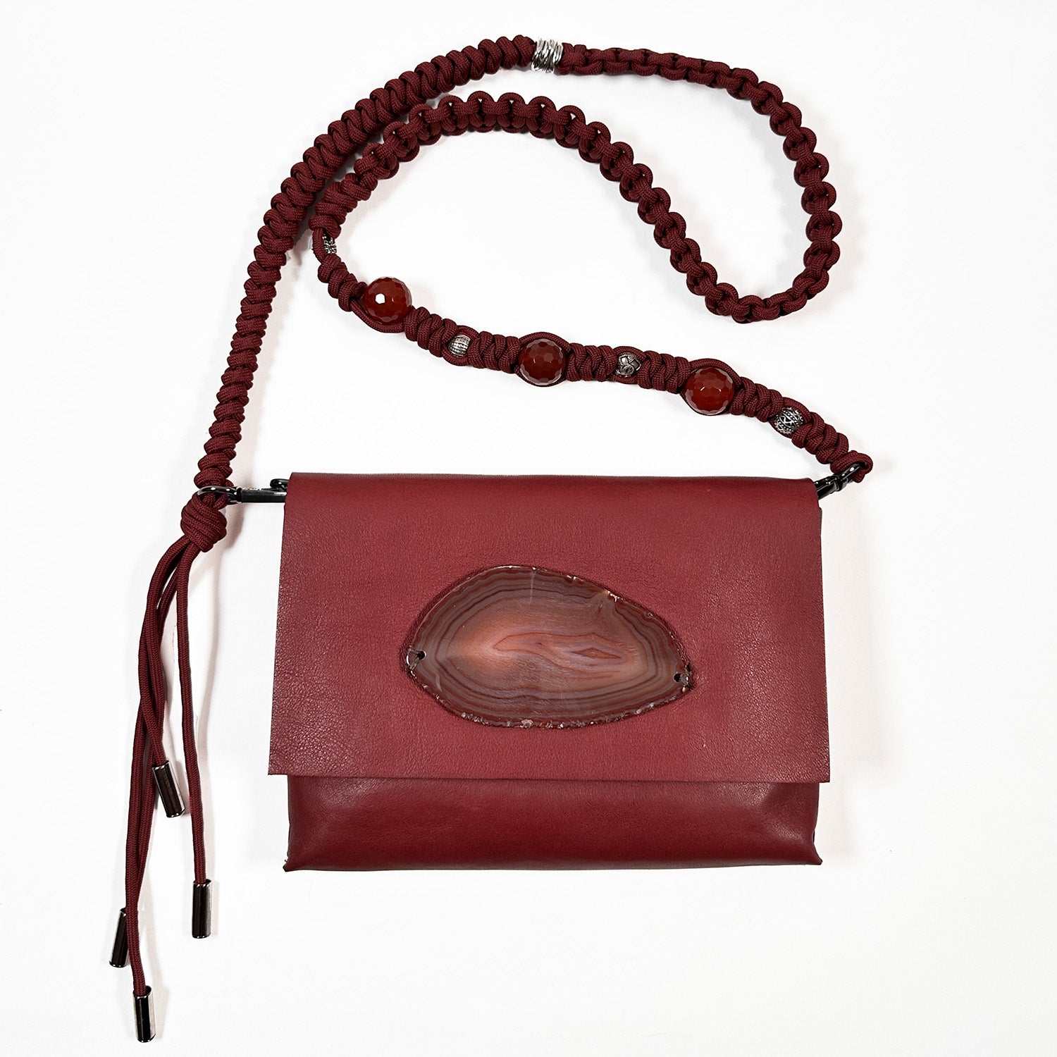Introducing the BAHAMA by evokewomen: a wine-colored Italian leather handbag featuring a knotted strap and a prominent agate stone accent on the front flap, designed for versatility.