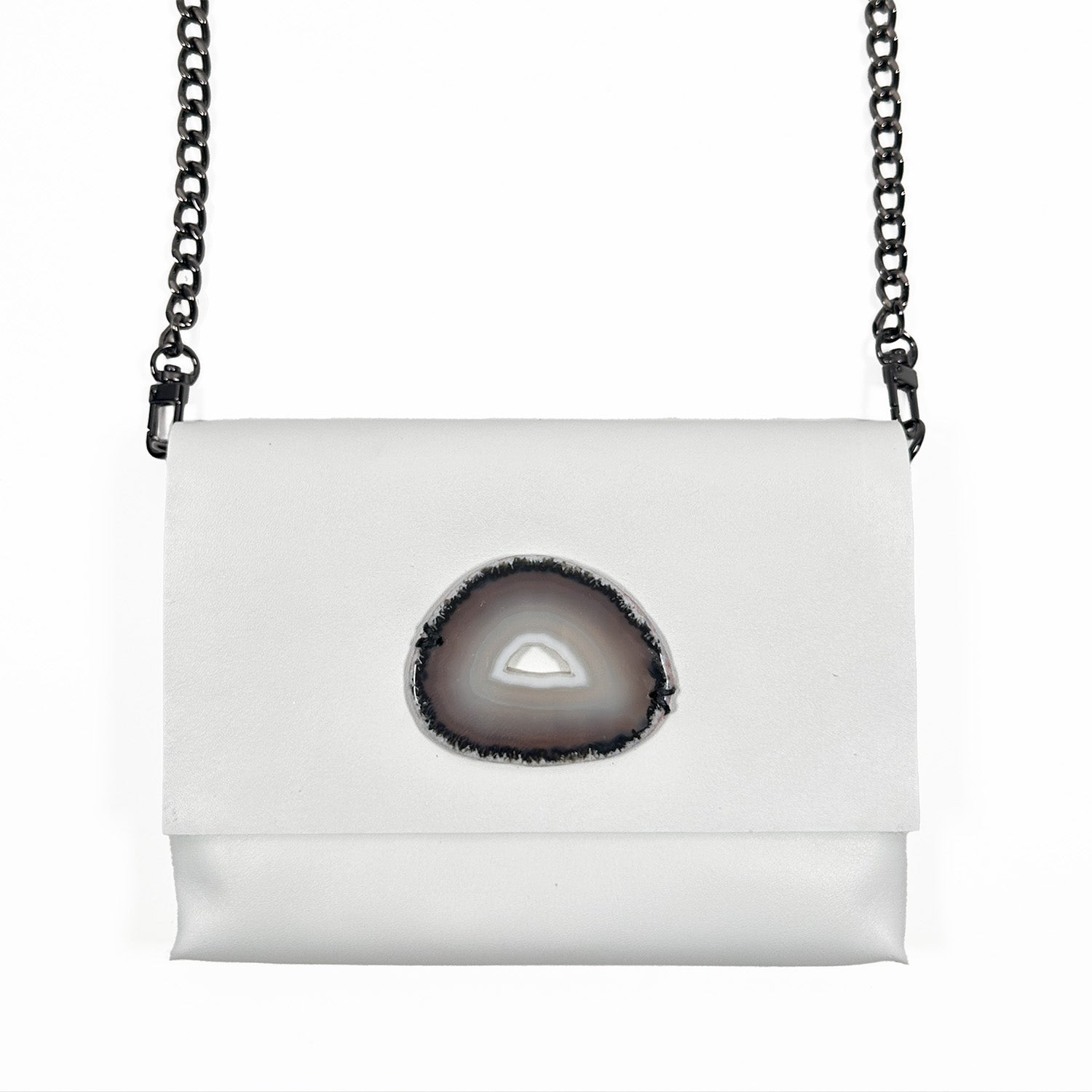 White leather crossbody bag featuring a dark brown and gray oval agate stone centerpiece, paired with a black gunmetal chain strap.