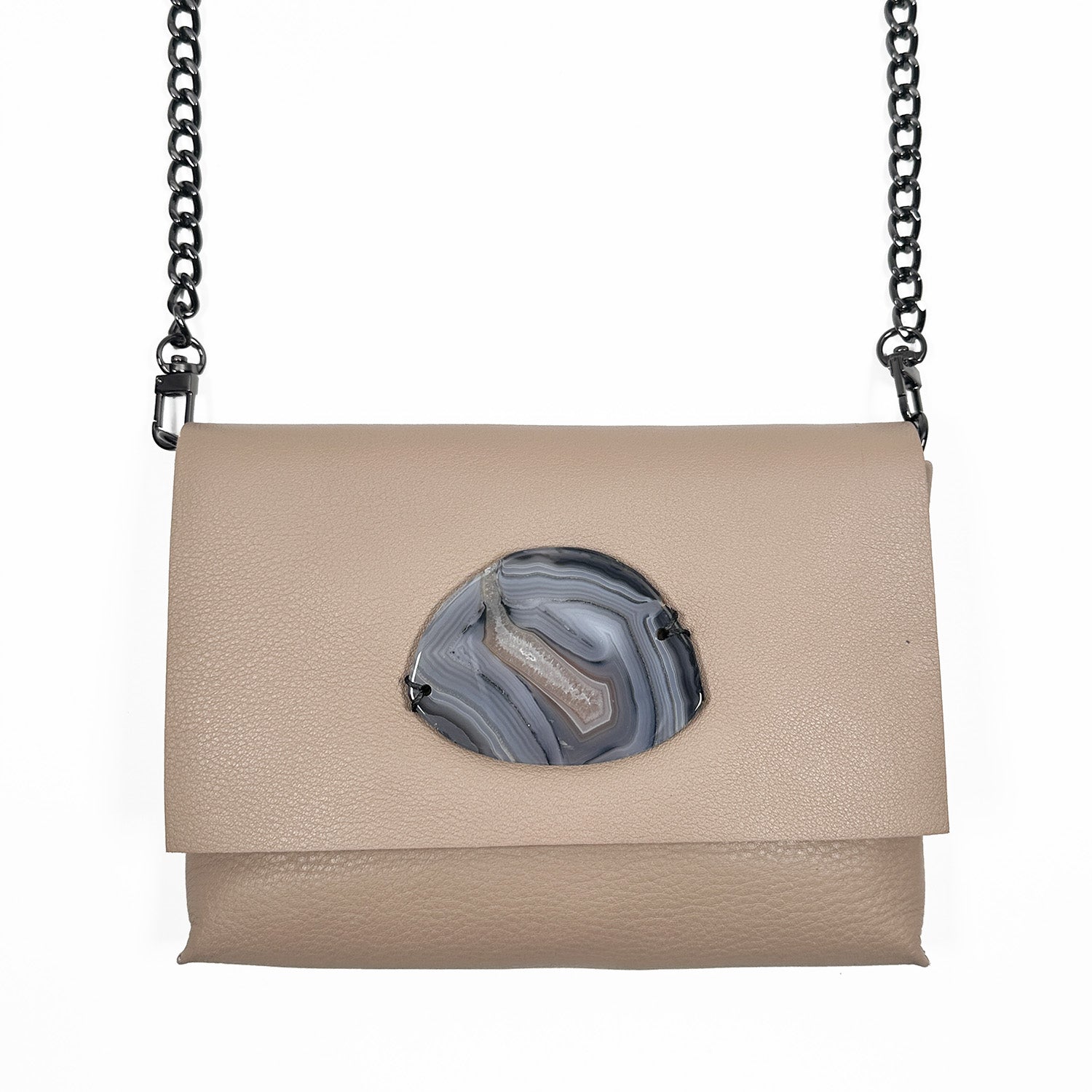 A taupe leather crossbody bag with a flap closure, featuring a round, polished gray agate stone accent in the center. The bag has a gunmetal chain strap.