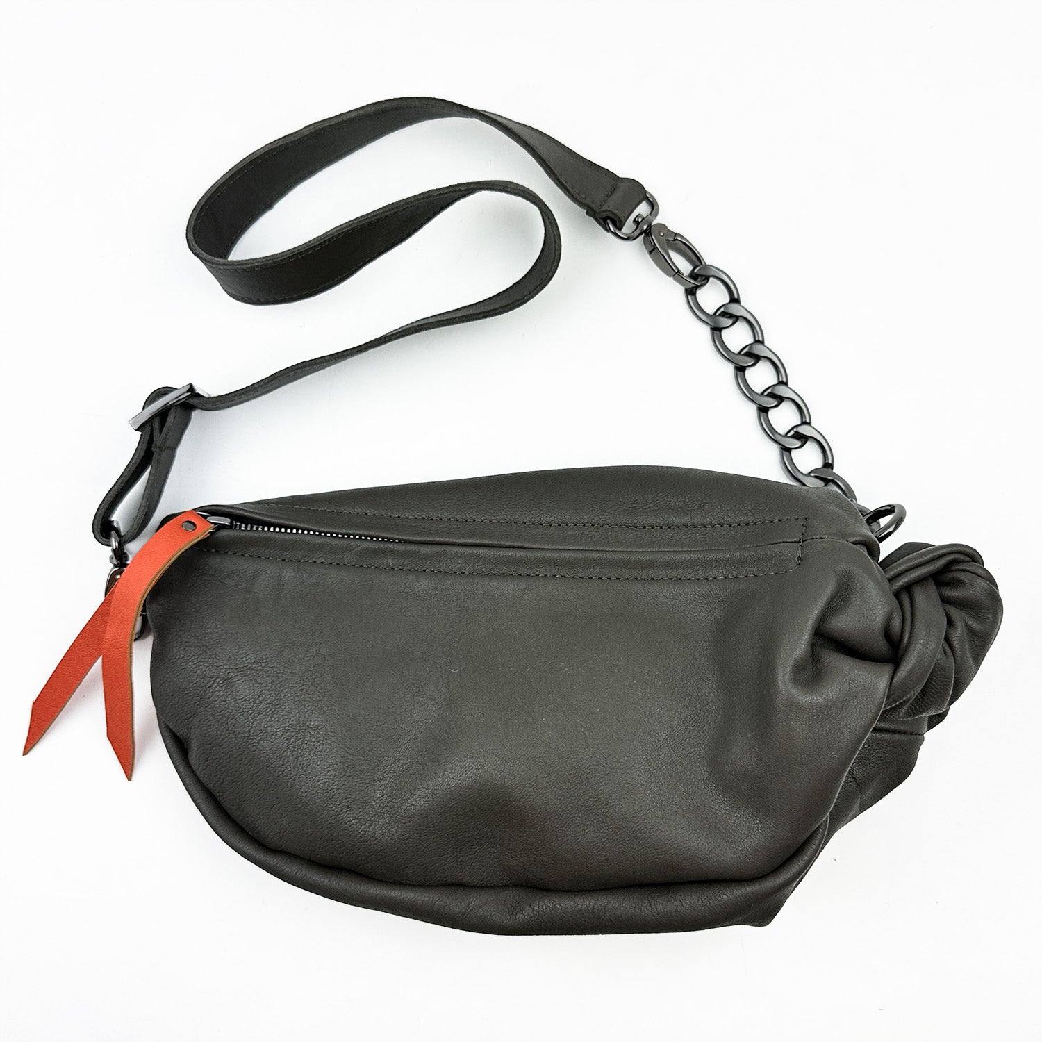 Introducing the LONDON crossbody bag by evokewomen, featuring a sleek olive-grey leather design complemented by a stylish black chain strap and an eye-catching orange leather puller, presented against a crisp white background.