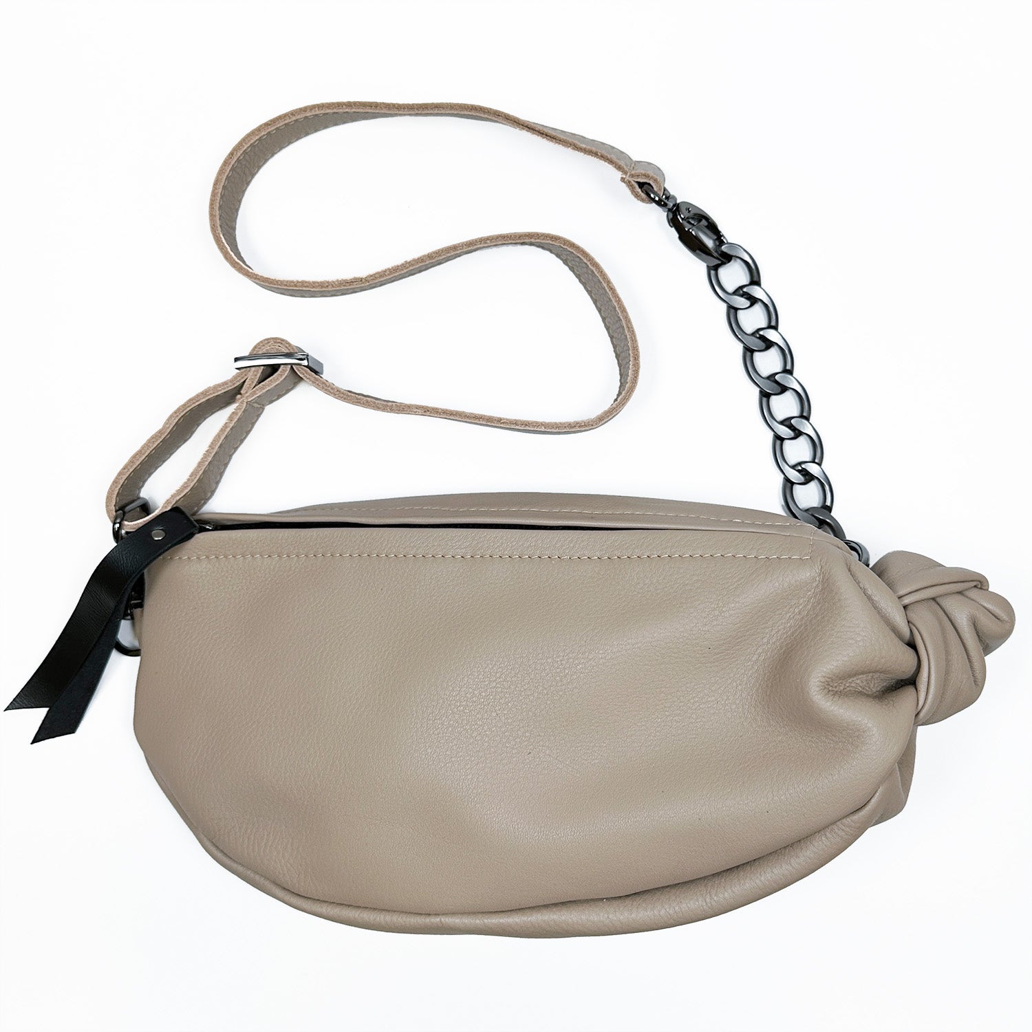 Introducing the LONDON - SAND sling bag by evokewomen, crafted from taupe leather with a stylish long strap and black chain accent. This trendy design includes a knotted detail on one side, making it a chic addition to any outfit.
