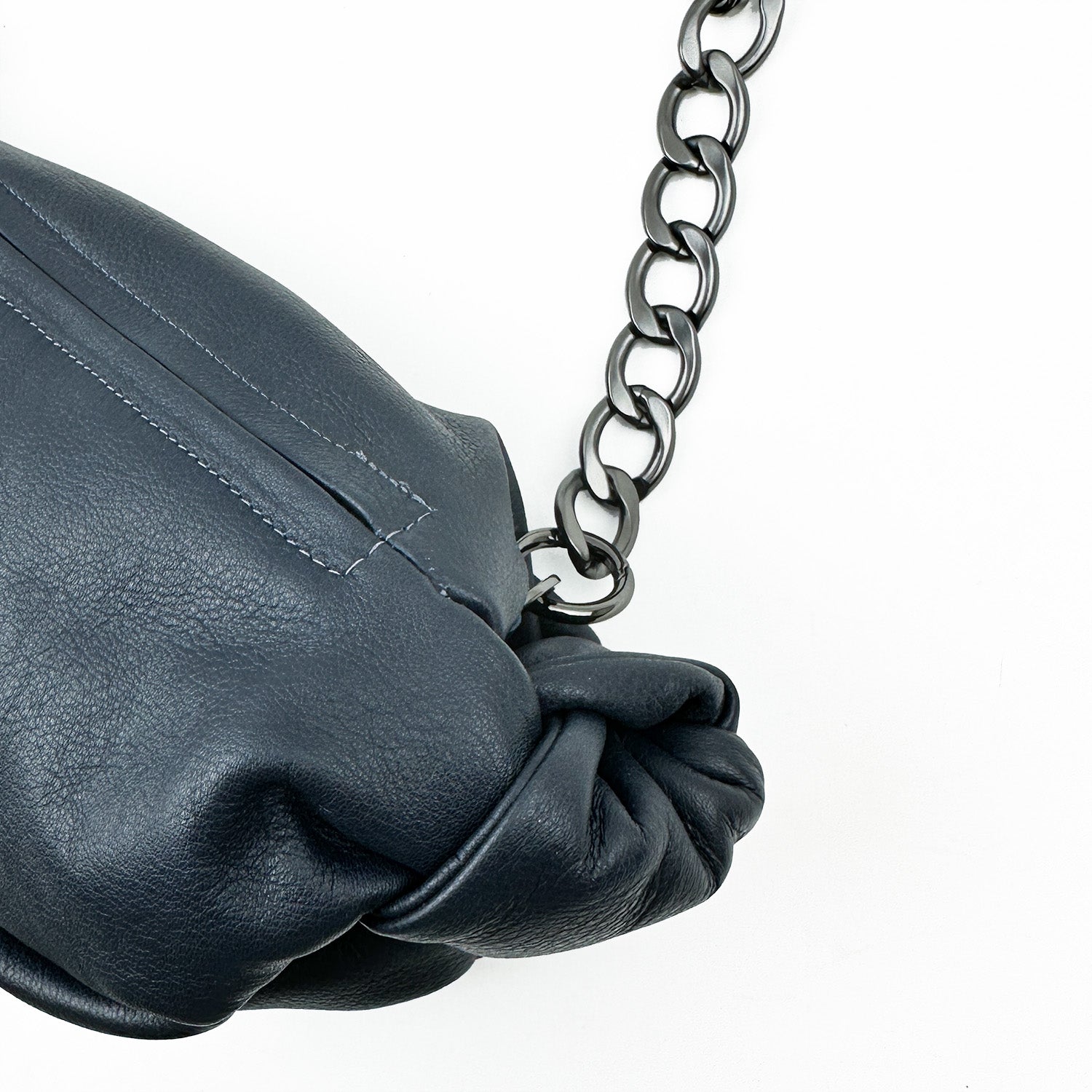 Close-up of a navy leather cross body bag named "LONDON" by evokewomen, featuring a silver chain strap on a white background.