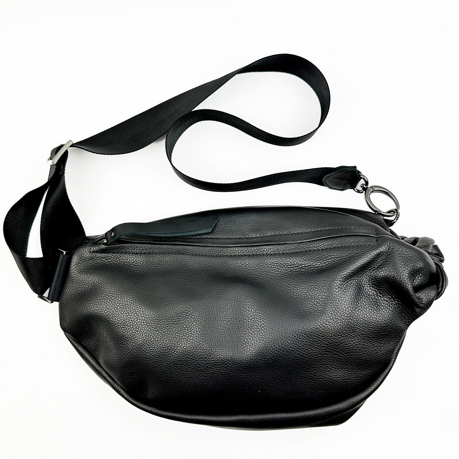 The evokewomen LULA - BLACK is a sling bag made of black leather, featuring an adjustable strap and zipper closure, showcased against a white background.