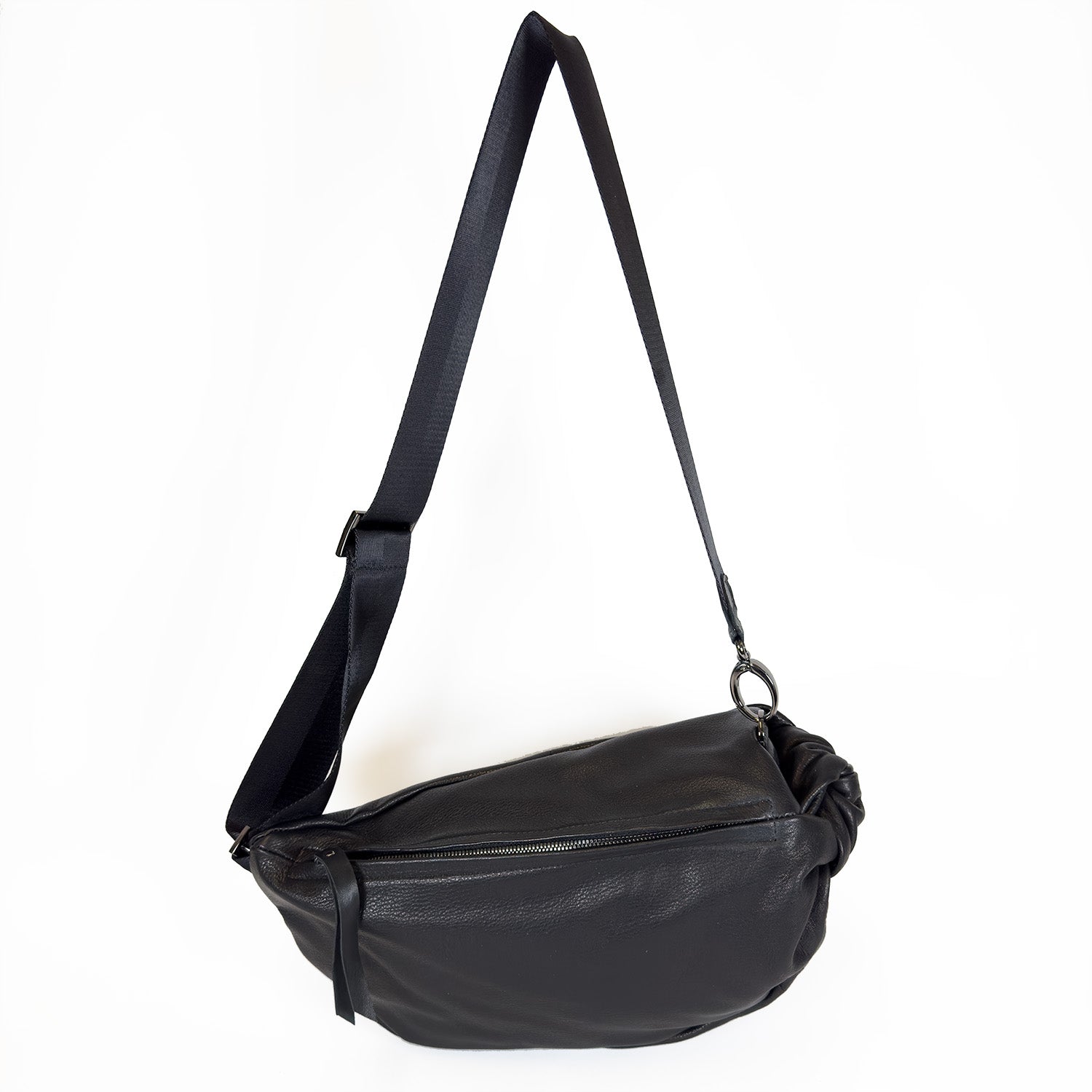 The LULA - BLACK by evokewomen, a sleek black leather crossbody bag with an adjustable strap and zipper closure, is elegantly showcased on a white background.