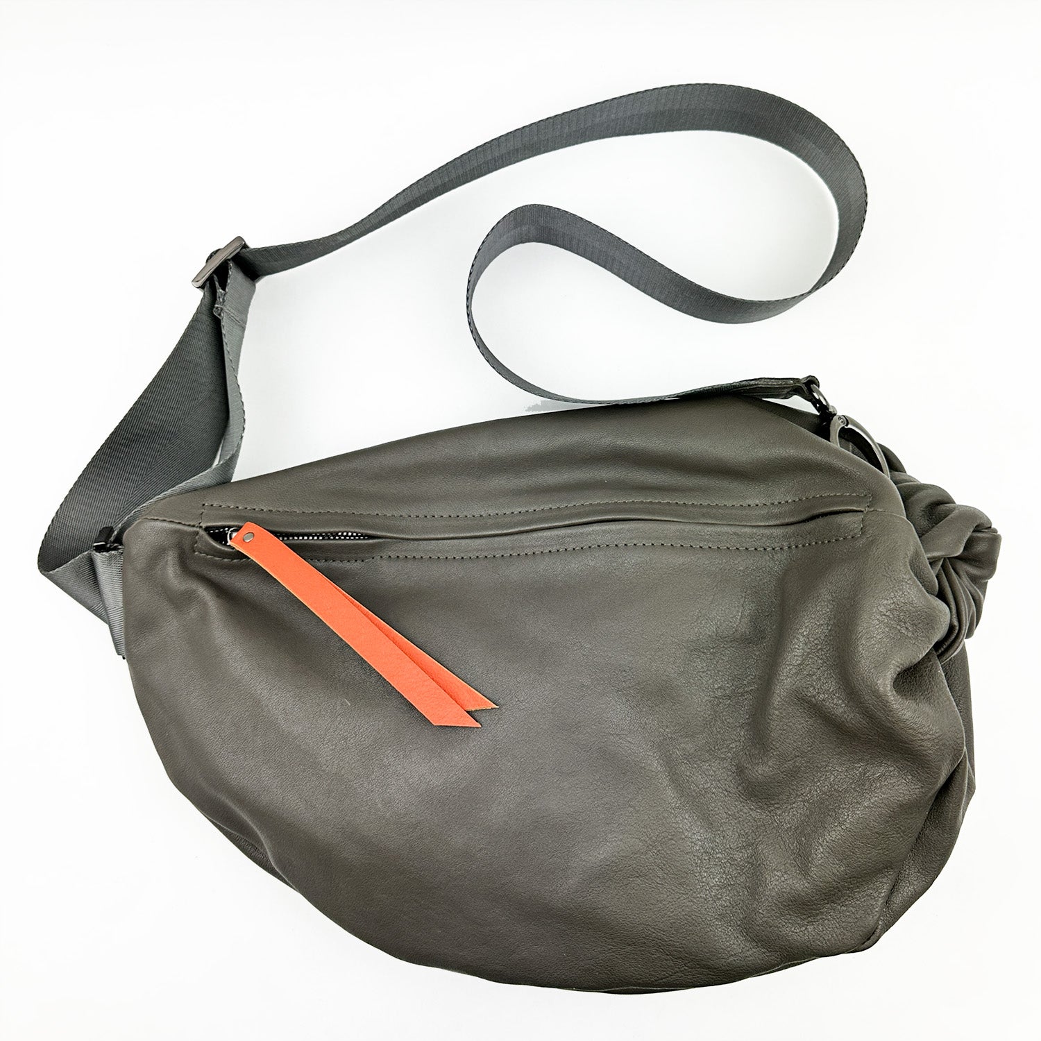 A LULA sling bag by evokewomen, featuring an olive-grey leather body with an orange leather puller and an adjustable strap.