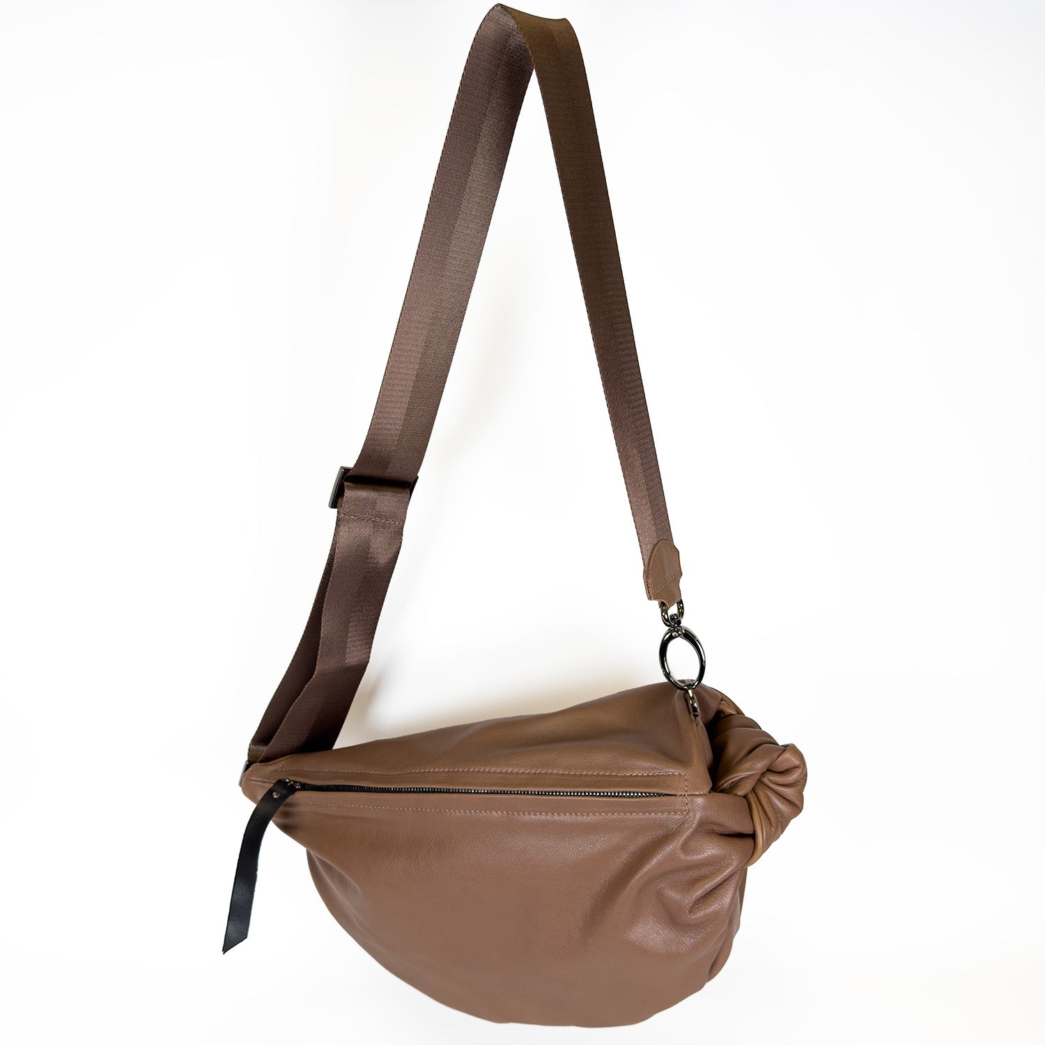 The LULA - NUTSHELL by evokewomen is a brown leather crossbody bag featuring an adjustable strap and zipper closure. It's ideal as a versatile sling bag, showcased against a plain white background.