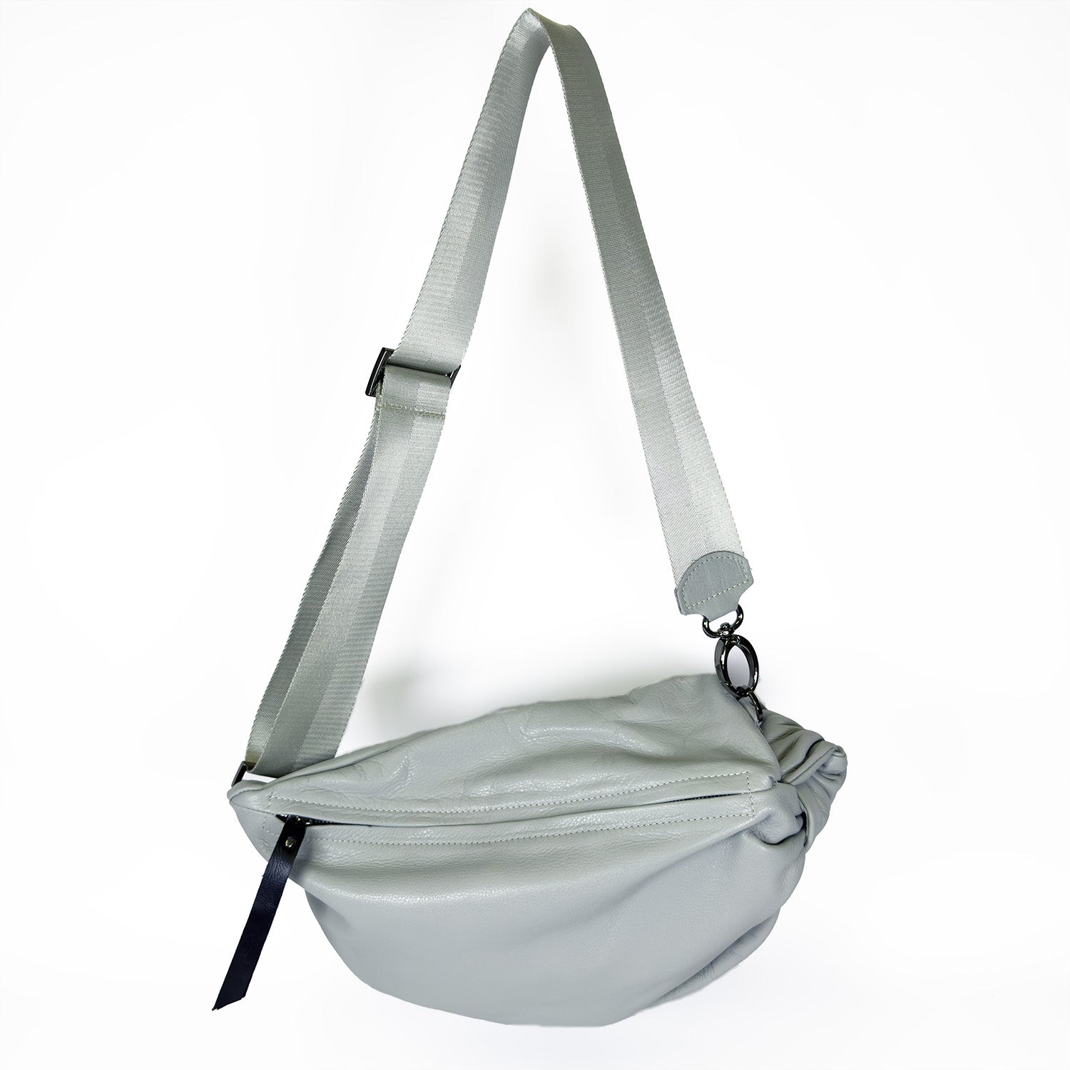 The LULA - LIGHT SMOKE sling bag by evokewomen features an adjustable strap and a zippered closure.