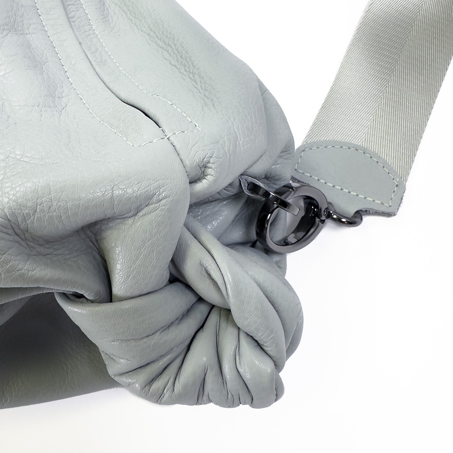 Close-up of the evokewomen LULA - LIGHT SMOKE crossbody bag in light gray leather, showcasing a knotted detail and a silver clasp on its strap.