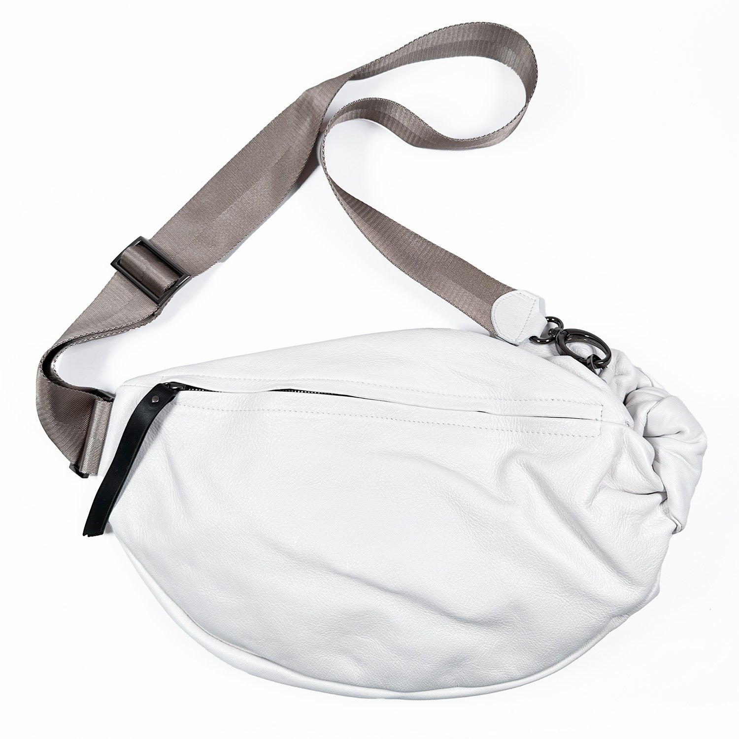 The LULA - WHITE / LIGHT TAUPE STRAP by evokewomen is a sleek snow-white leather crossbody bag featuring a stylish gray adjustable nylon strap and a functional black zipper, making it ideal for those who value both style and practicality in a sling bag.