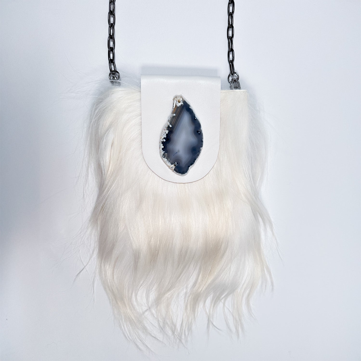 The MIA - WHITE handbag by evokewomen is a white furry crossbody bag featuring a chain strap and a geode detail on the flap.