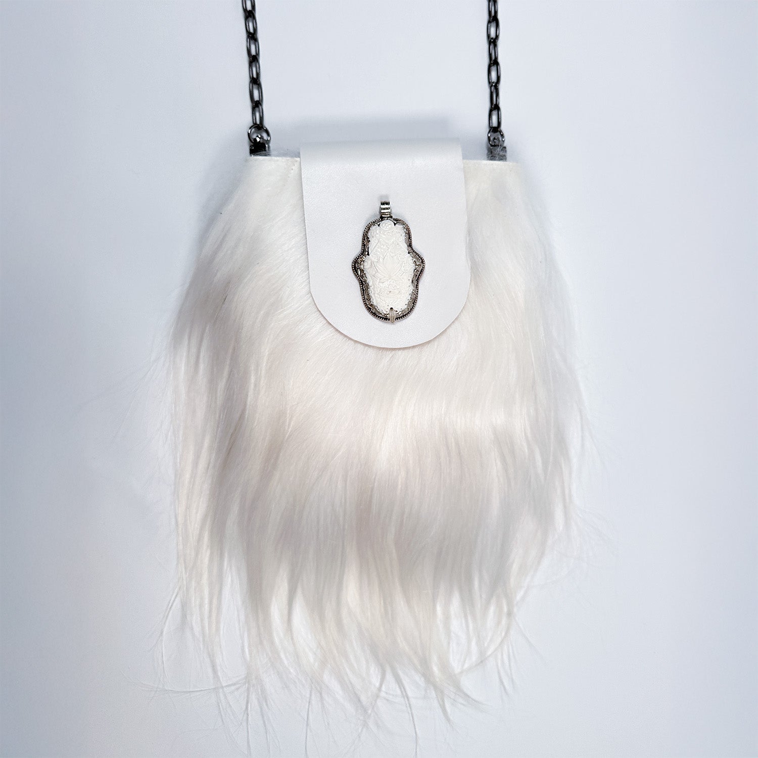 The MIA - WHITE, a chic accessory from evokewomen, features a white furry texture adorned with a silver clasp and chain strap, elegantly displayed against a plain background to highlight its versatile design.