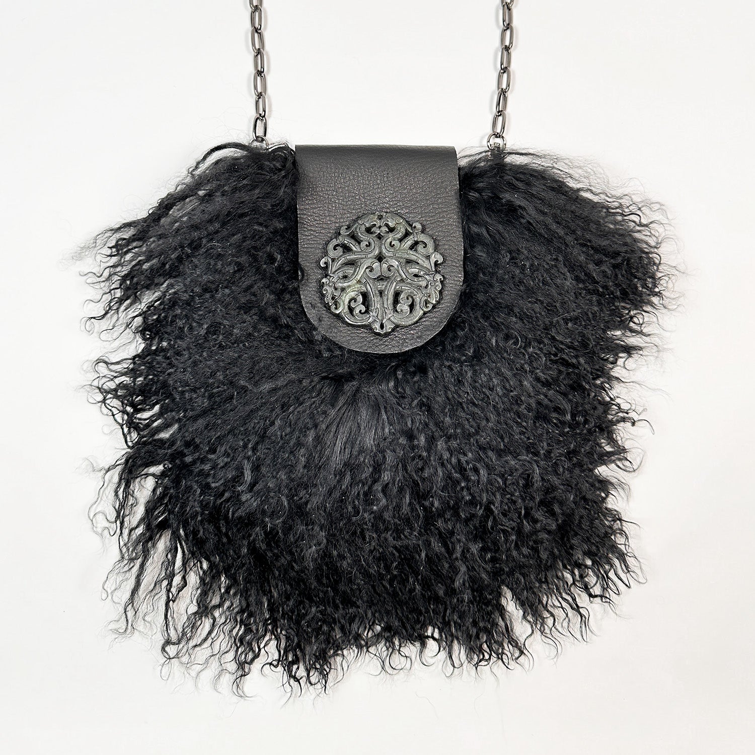 The MIA - BLACK crossbody bag from evokewomen features a chic metal chain strap and showcases a curly Mongolian lamb fur texture, with the flap adorned by a detailed metal emblem.