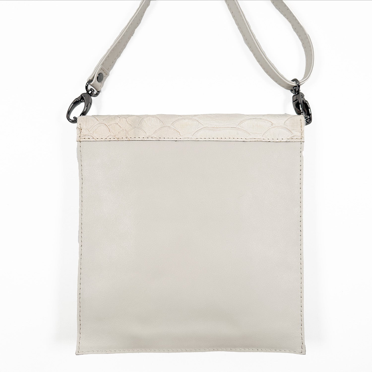Back view of an off white, portrait-shaped crossbody leather bag featuring an off white leather strap and gunmetal buckles, displayed on a white background.