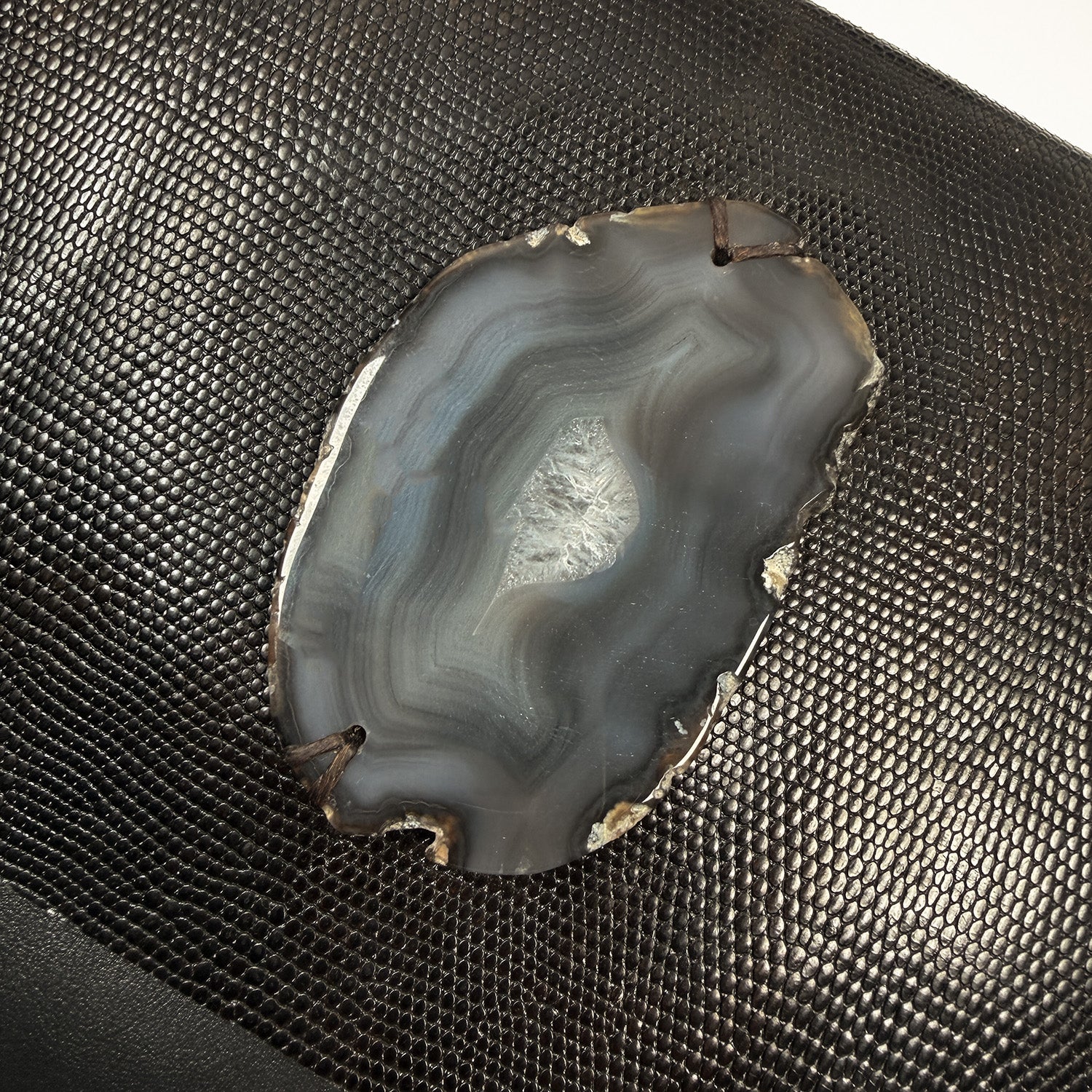 Geode slice on a textured dark brown Lizzard skin embossed leather.
