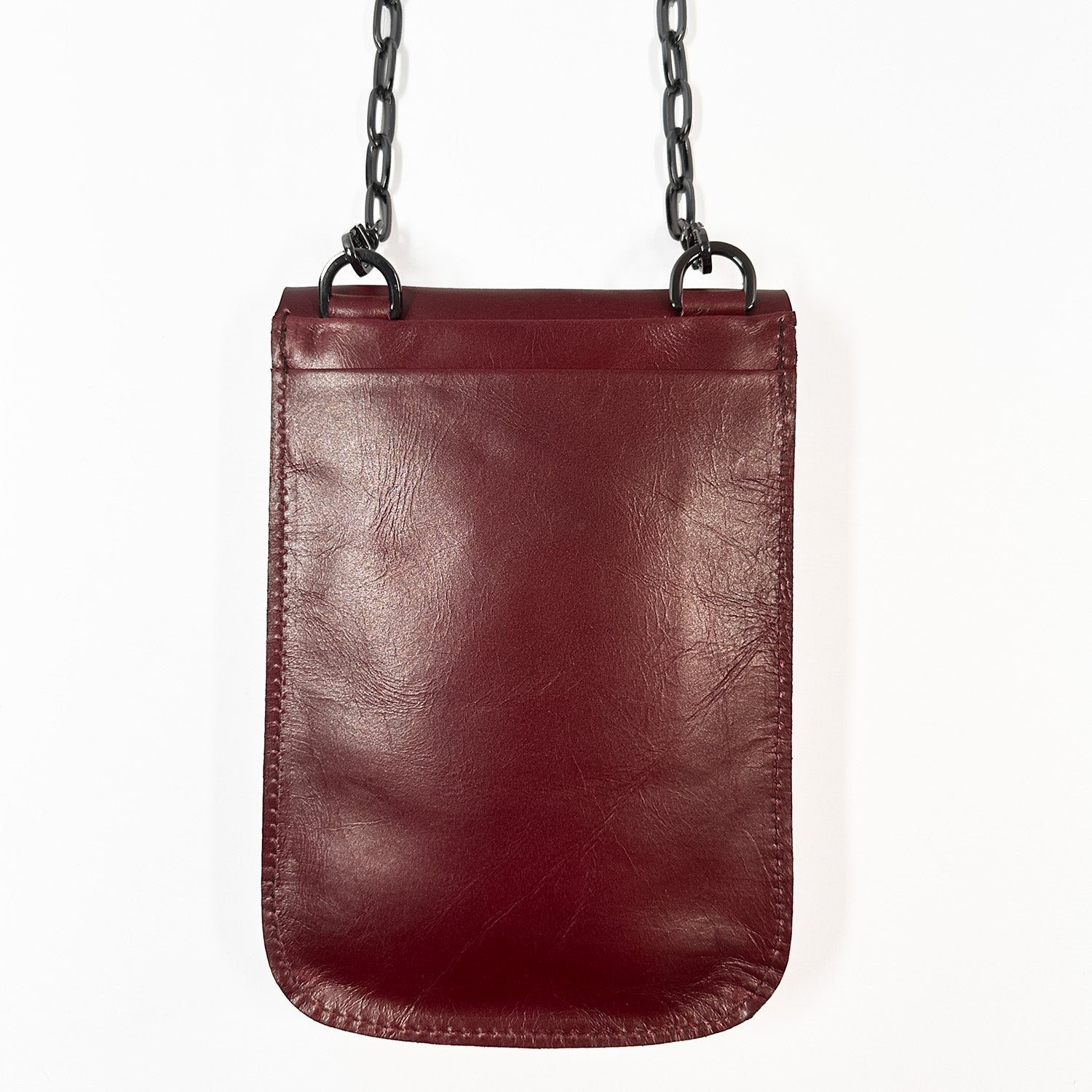 The PAULINA - wine by evokewomen is a small rectangular crossbody bag made from sumptuous Italian leather, adorned with a chic black chain strap hanging elegantly against a pristine white background—a true festival essential.
