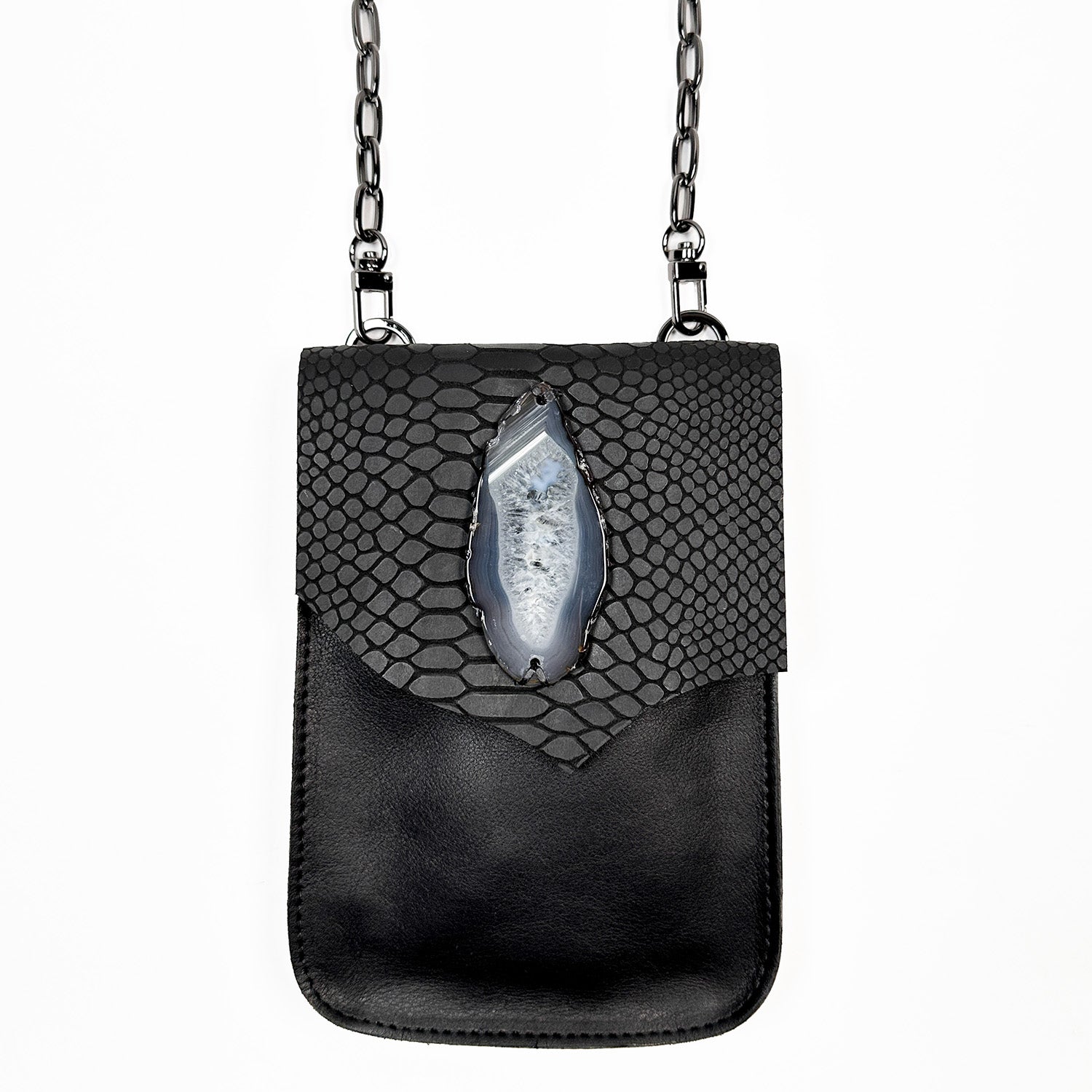 The PAULINA - BLACK SNAKE LOOK crossbody bag by evokewomen is a compact, rectangular accessory made from Italian leather. It includes a shoulder chain and features a decorative stone on the front flap, making it a must-have for festivals.
