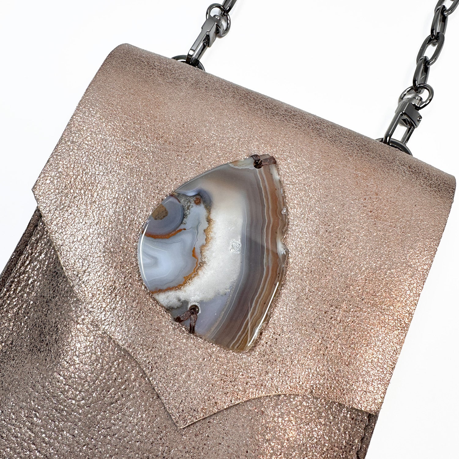 The PAULINA - antique bronze crossbody bag by evokewomen is a compact, rectangular accessory made from Italian leather. It includes a shoulder chain and features a decorative stone on the front flap, making it a must-have for festivals.