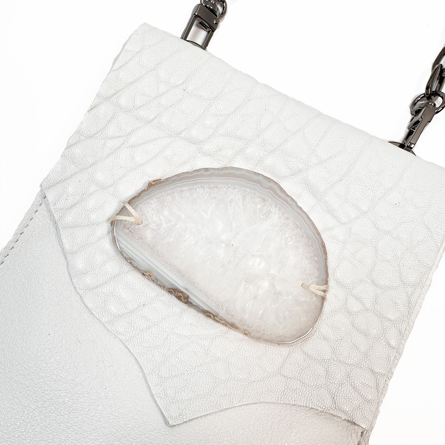 The PAULINA - white by evokewomen is a chic leather crossbody bag that showcases a almond-shaped agate accent and a fashionable chain strap.