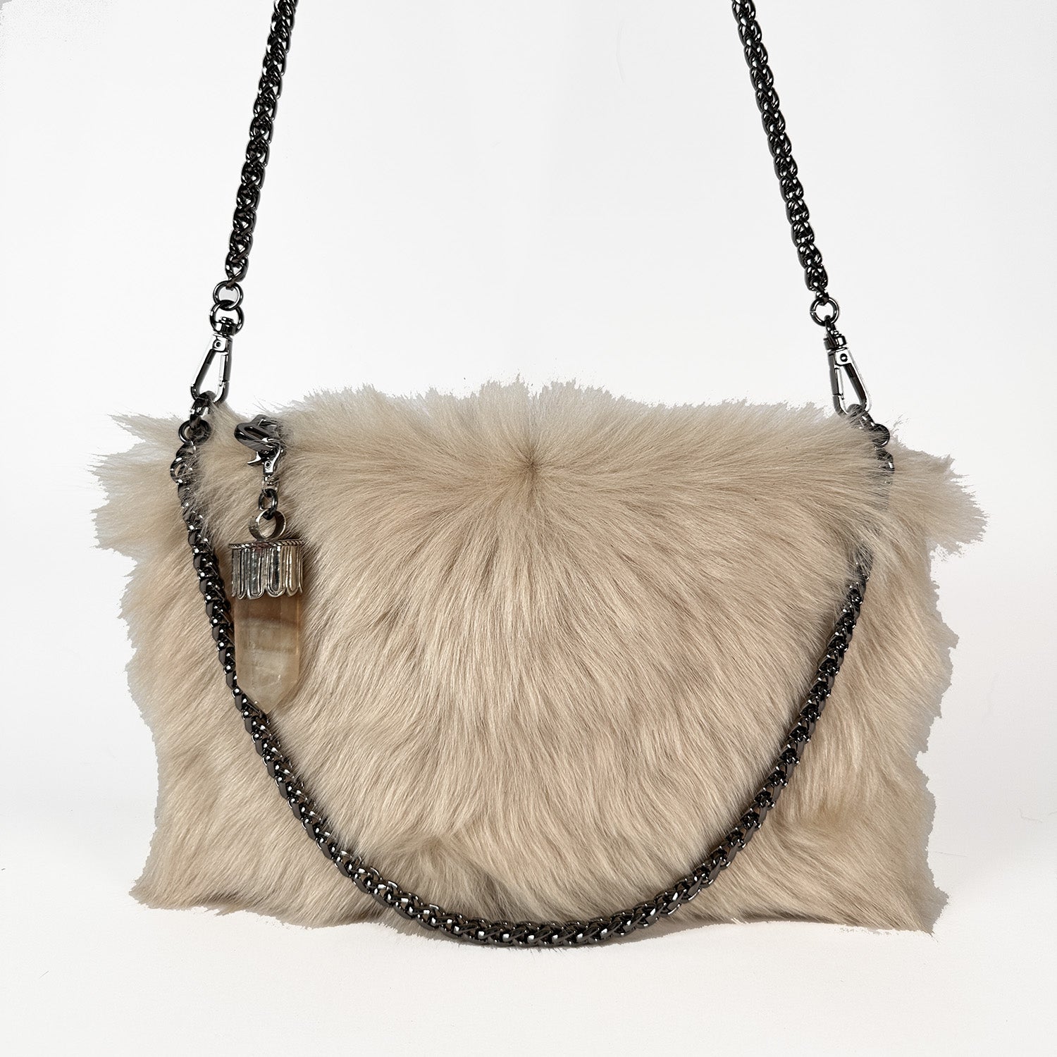 Experience the Fluffy Toscana Lamb Fur handbag from evokewomen, known as the POPPY - CREAMY BEIGE. This sophisticated piece showcases a black chain strap and is accented with a delicate tassel ornament for added flair. Versatile in design, it also functions as a crossbody bag, making it an ideal choice for any occasion.