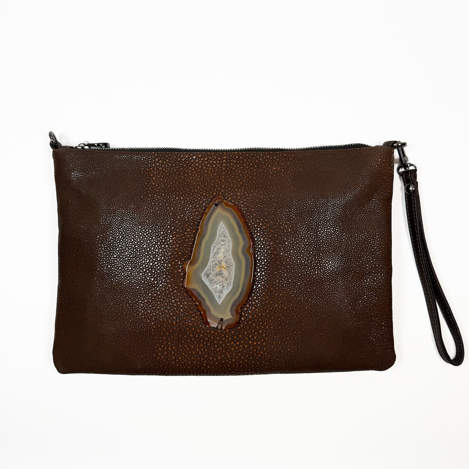 Brown embossed Stingray leather clutch adorned with oval shaped agate slice on white background.