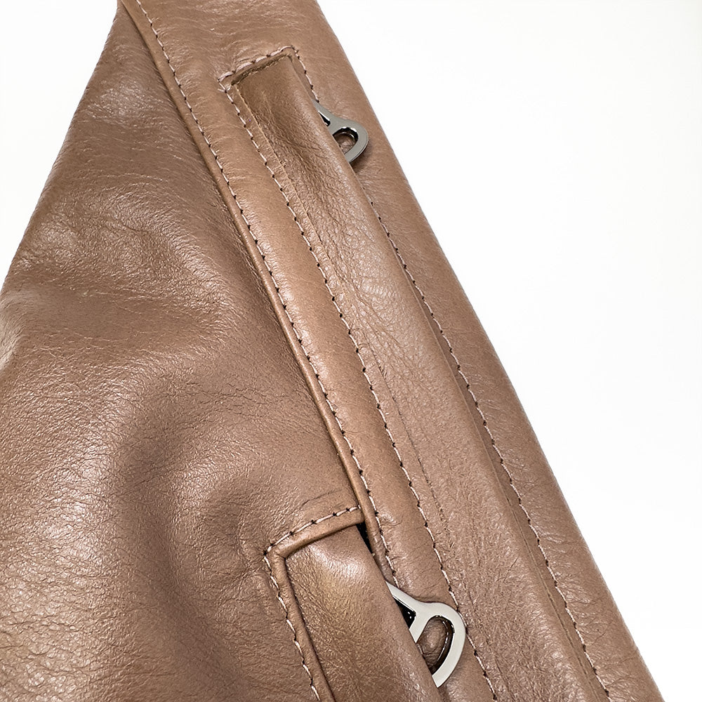 Close-up of a brown Sienna - nutshell sling bag by evokewomen, featuring visible stitching and metal rings.