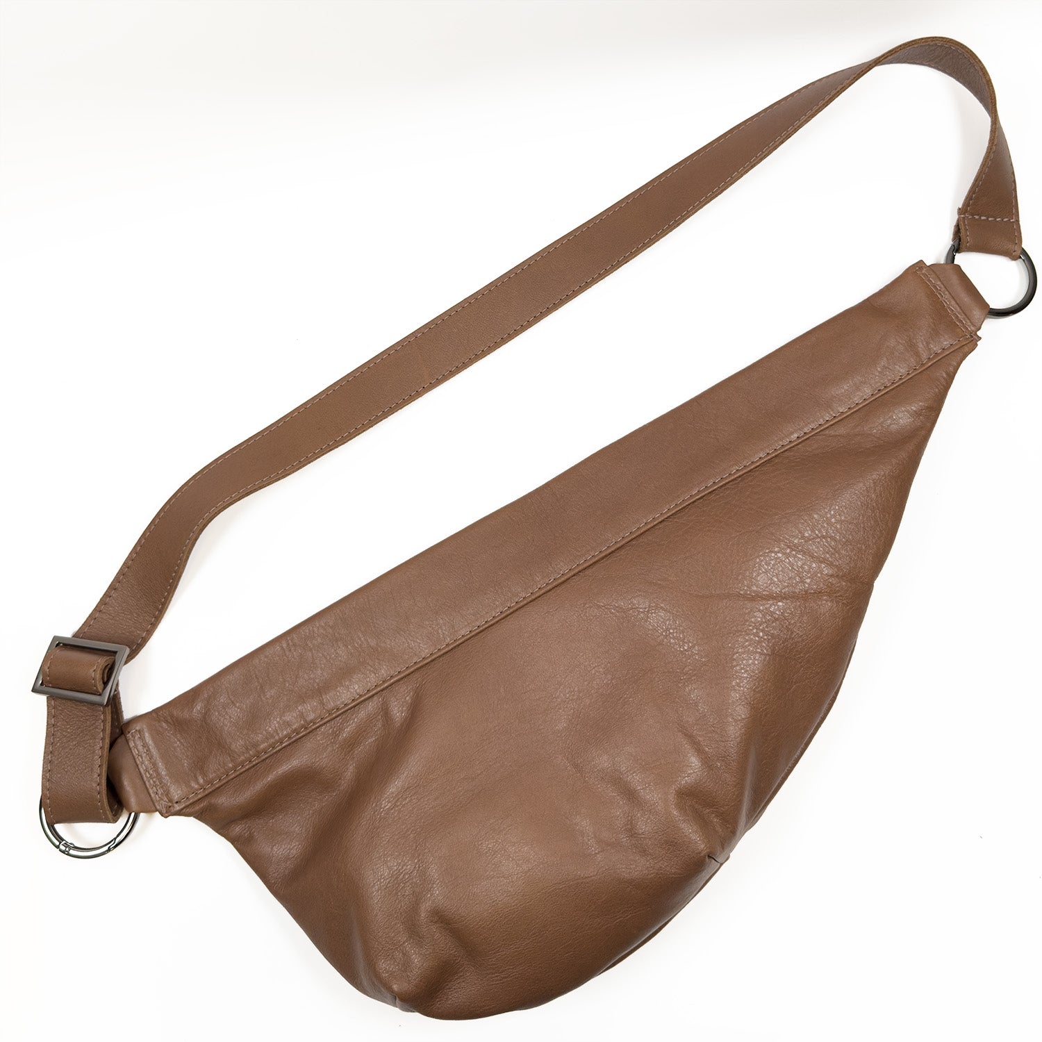 The Sienna - nutshell by evokewomen is a brown leather crossbody featuring an adjustable strap and silver rings on each end.