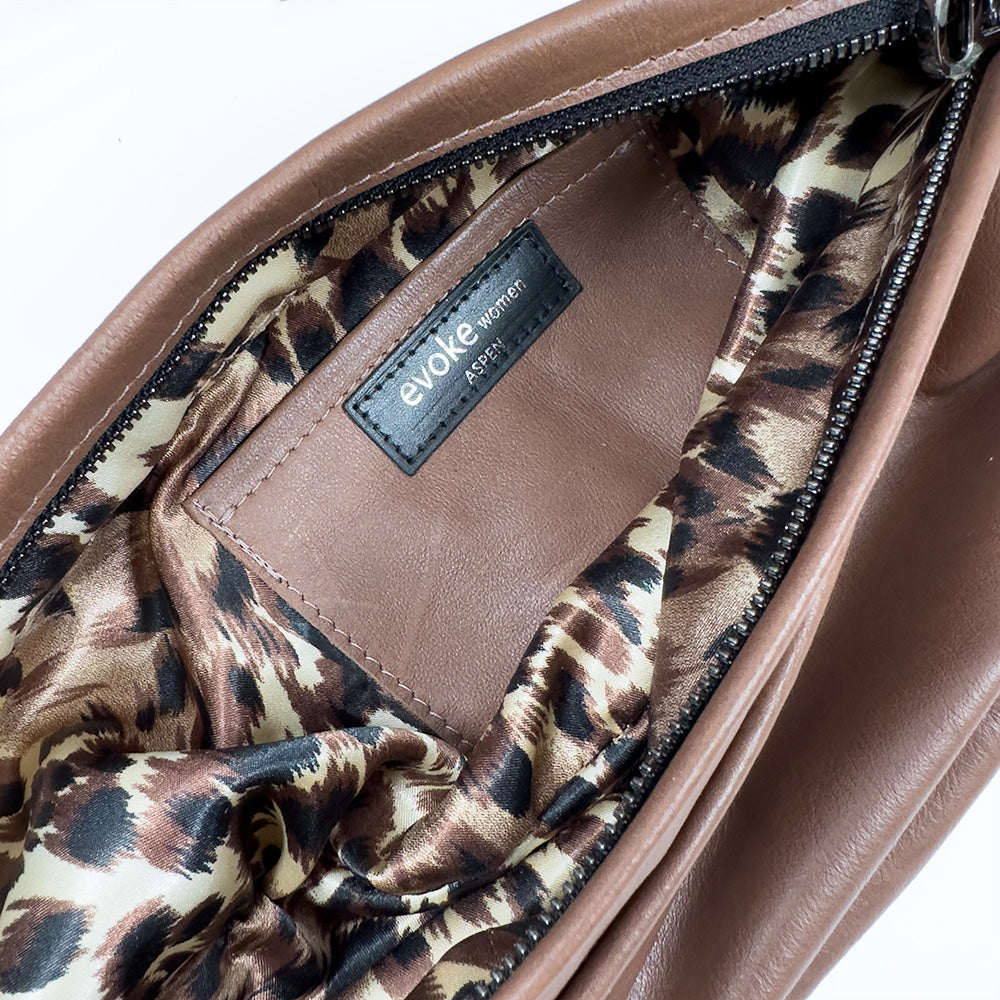 Introducing the Sienna - nutshell: A brown leather handbag with a chic leopard print lining, marked with the "evokewomen" label. This elegant cross-over bag is ideal for those who value both style and functionality.