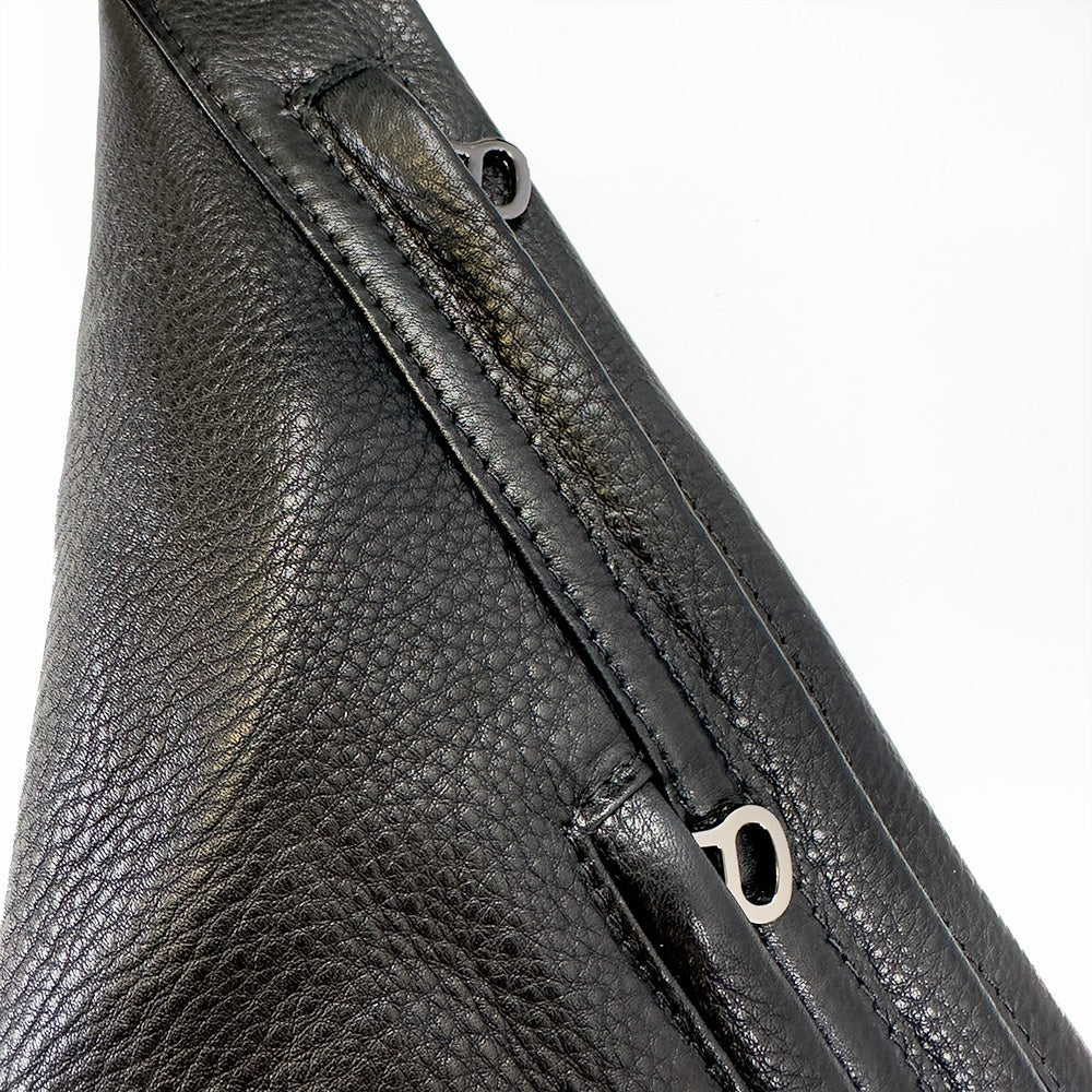 Close-up of the evokewomen's Sienna - black Sling Bag, an accessory featuring a textured leather surface and two zippers with metal pulls.