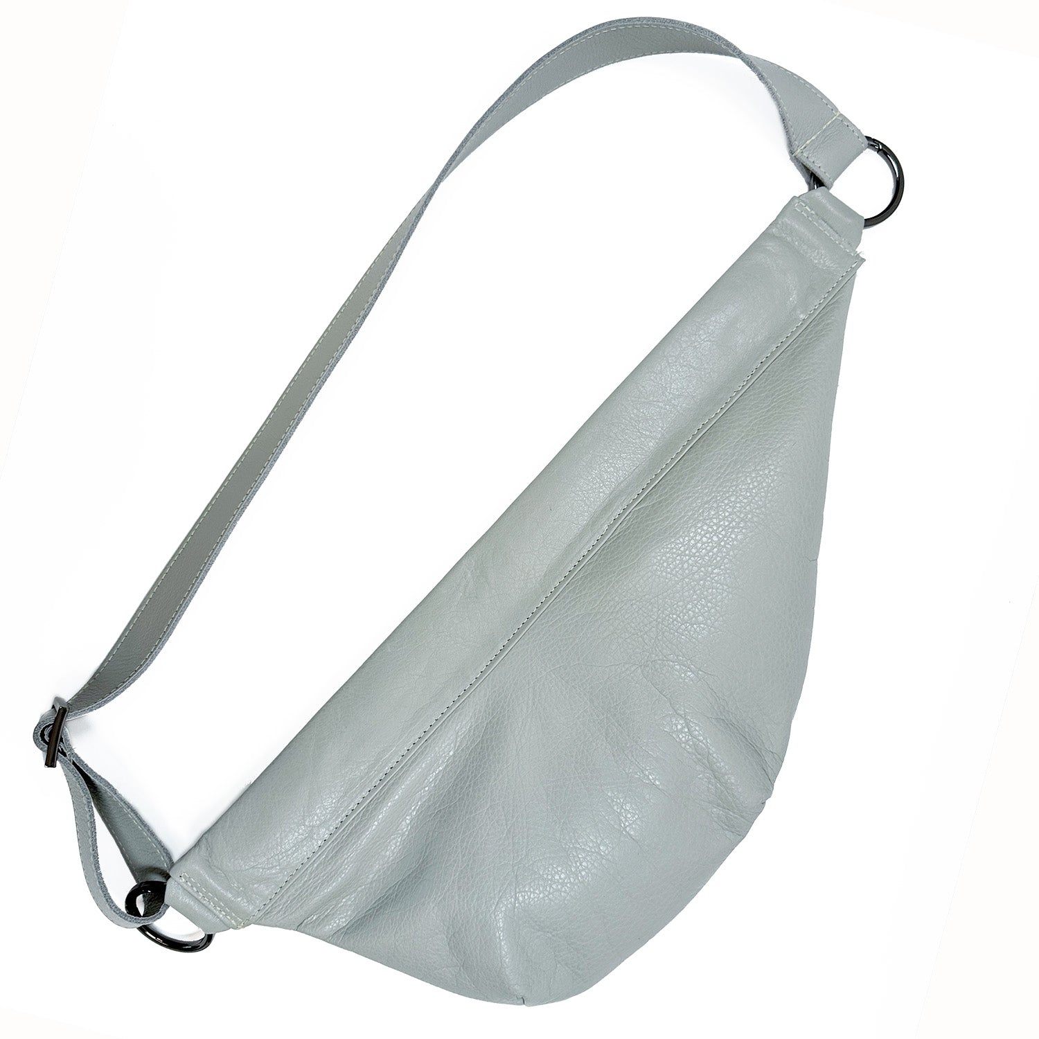 The Sienna in light smoke & tassel by evokewomen is a gray leather sling bag with an adjustable strap, boasting a versatile and minimalistic design with metal rings on each end.