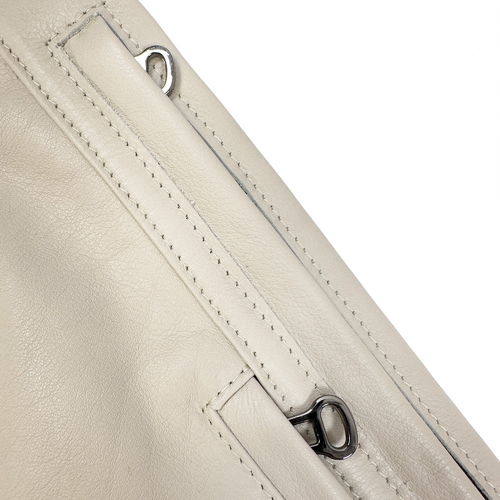Close-up of a beige leather surface with noticeable zipper and stitching details, reminiscent of the exquisite craftsmanship found in an evokewomen Sienna - putty sling bag.