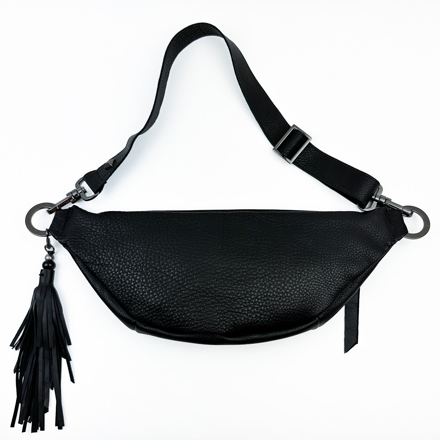 The STELLA - BLACK sling bag by evokewomen features black leather with an adjustable strap and a tassel decoration on one side, set against a white background.
