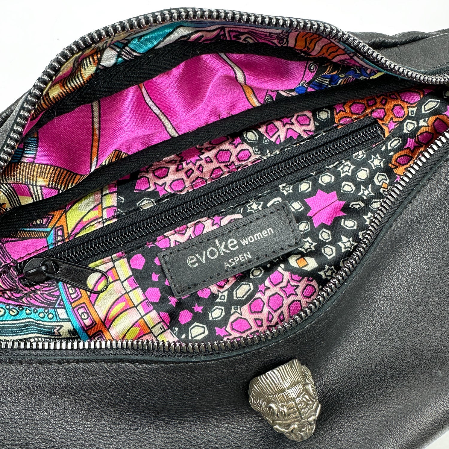 Unzip the STELLA - BLACK leather bag from evokewomen to reveal a vibrant, patterned interior and find comfort in its adjustable strap. It includes a zippered pocket along with a label that states "evokewomen," capturing the chic essence reminiscent of the Stella Sling bag's design.