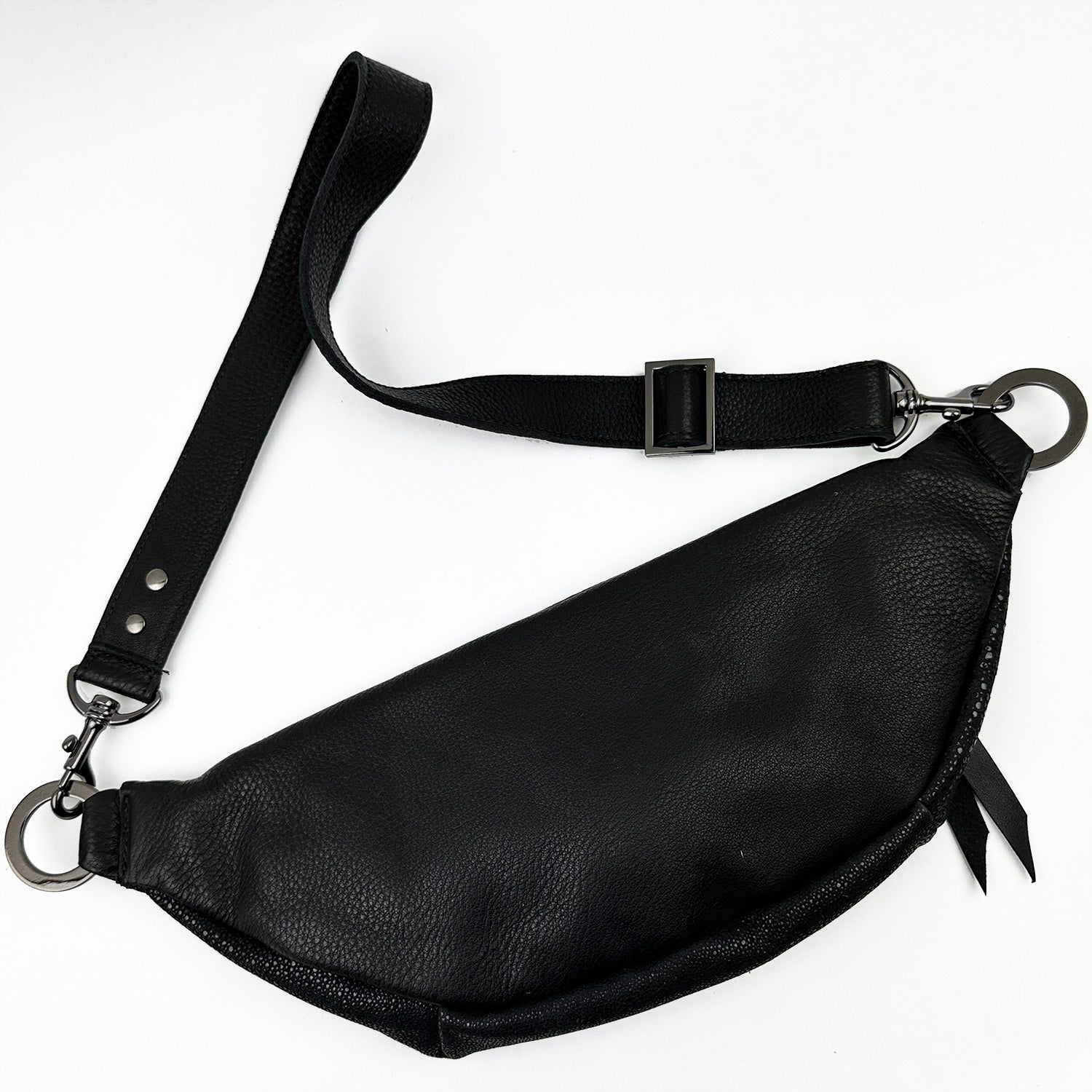 The STELLA - BLACK STINGRAY crossbody sling bag by evokewomen, featuring an adjustable strap and metal clasps, is showcased on a white background.
