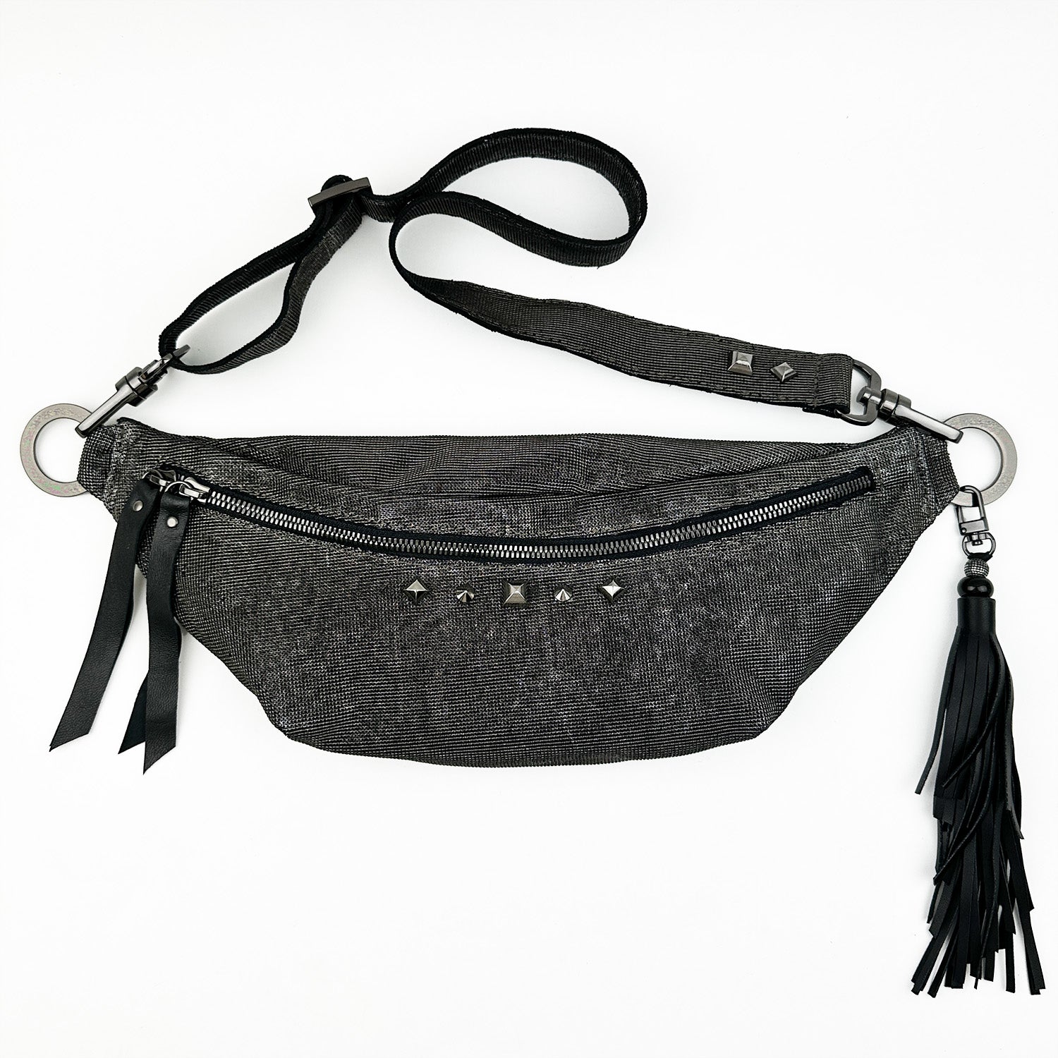 Introducing the STELLA - GUNMETAL TEXTURE by evokewomen, a versatile black waist bag featuring an adjustable strap with metal rings that transforms seamlessly into a crossbody bag. This stylish accessory includes a zipper closure, fringed tassel, and eye-catching stud details.