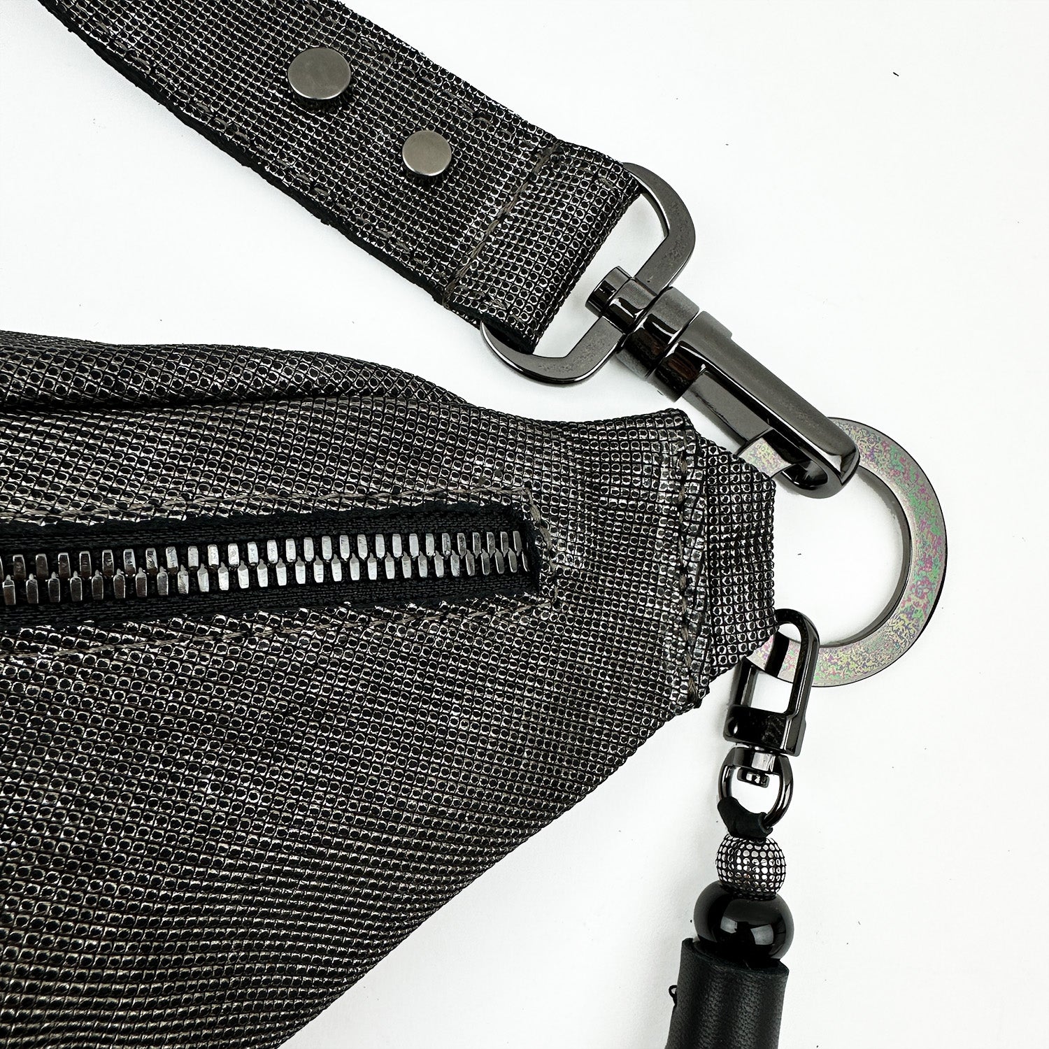 Close-up of the STELLA - GUNMETAL TEXTURE sling bag by evokewomen, featuring a black zipper and metal clasp on the strap, set against a white background.