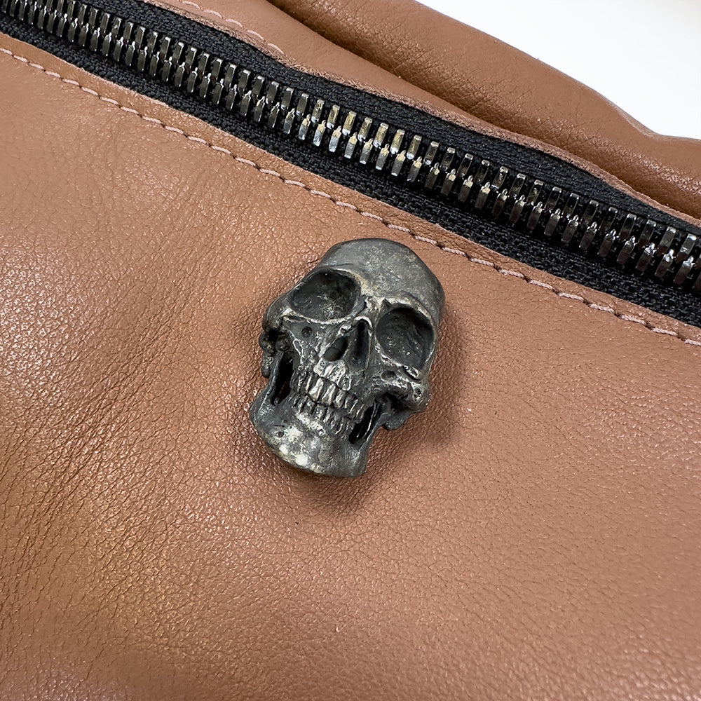The STELLA - western brown sling bag by evokewomen features a small metal skull decoration and comes with a zipper for secure storage.