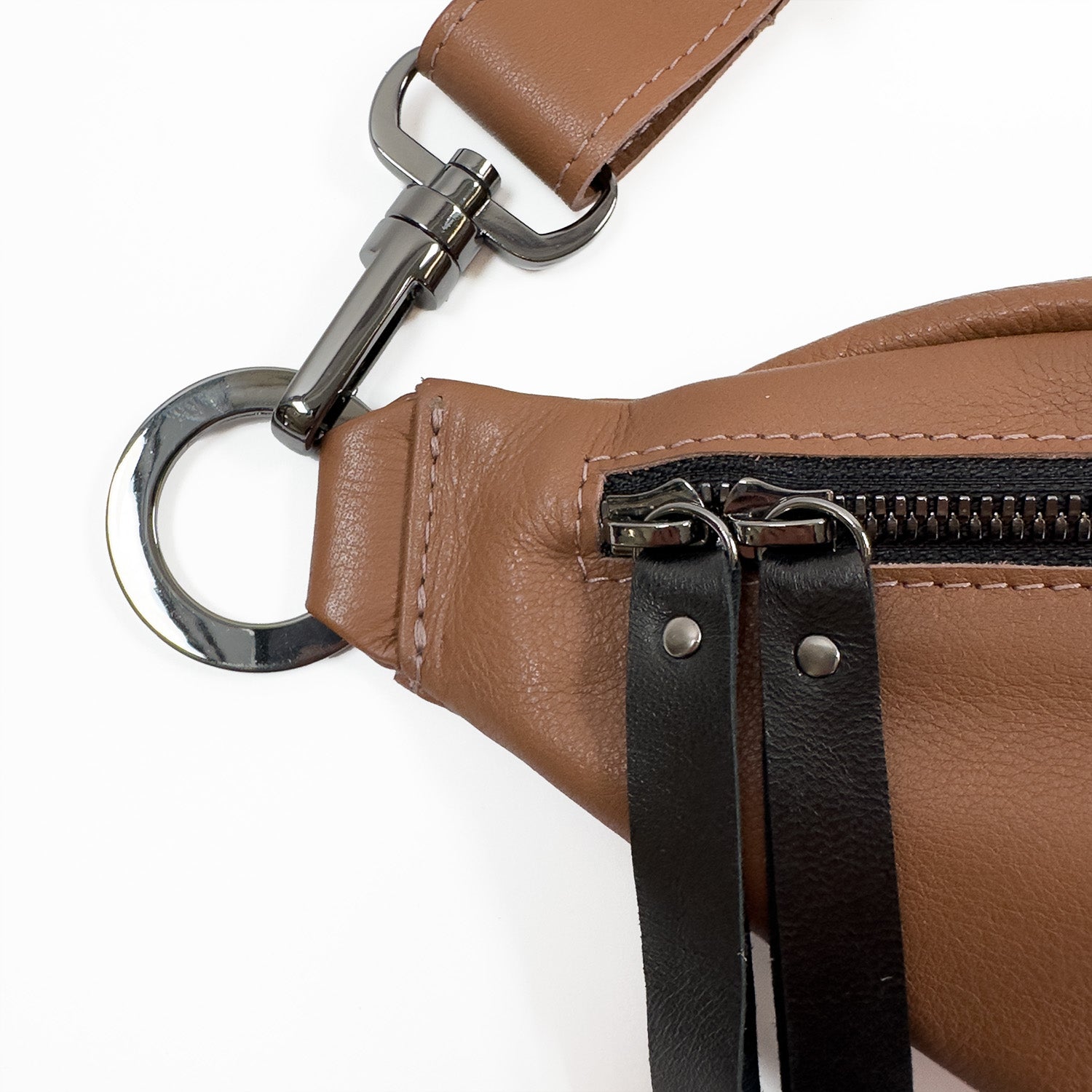 Close-up of the STELLA - western brown sling bag by evokewomen, featuring a zipper, metal ring, and black strap accents on a white background.