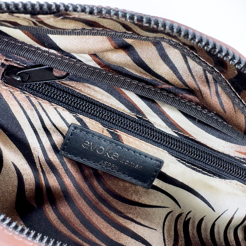 Explore the STELLA - western brown leather bag from evokewomen, featuring a zebra-patterned lining and a sleek black zipper pocket. Inside, you'll find a black label that reads "clowe designed in Spain." Enhance your fashion accessory collection with this unique piece.