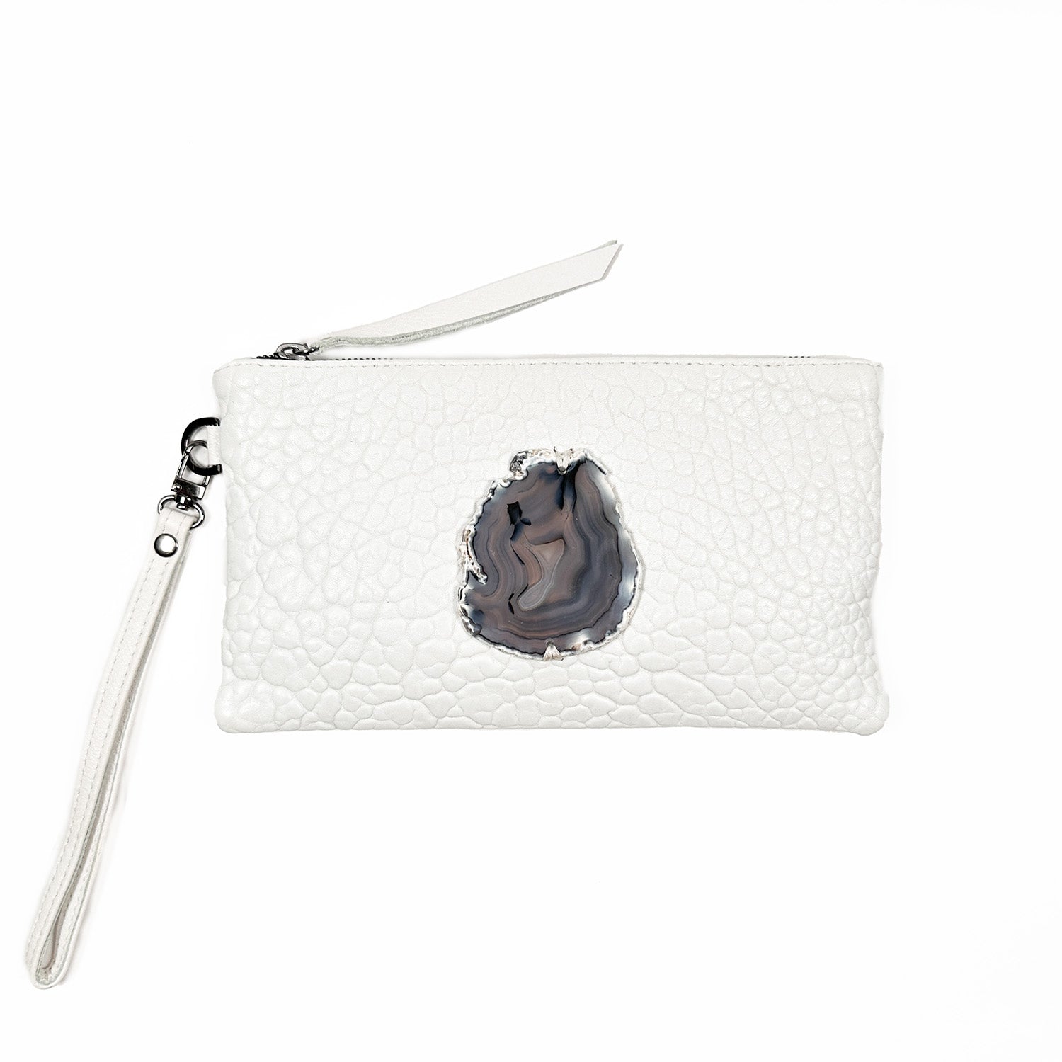 The VICTORIA - white clutch from evokewomen showcases a textured leather design adorned with a central agate stone accent. It includes a zipper closure and comes with a detachable wrist strap, allowing for easy conversion into a wristlet for stylish versatility.
