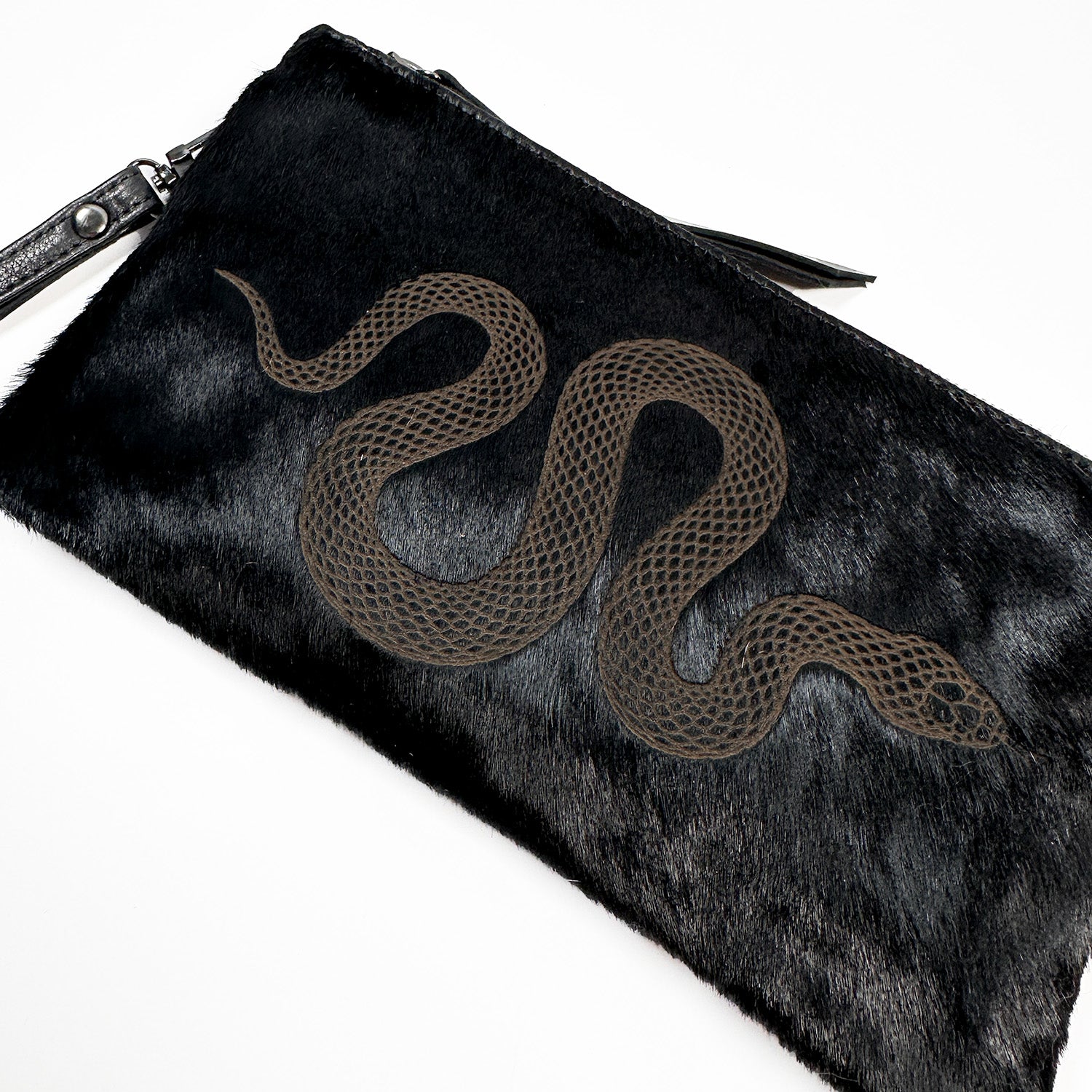 Discover the VICTORIA Bag by evokewomen: a black textured clutch that offers versatile style with an intricate laser snake design on the front.