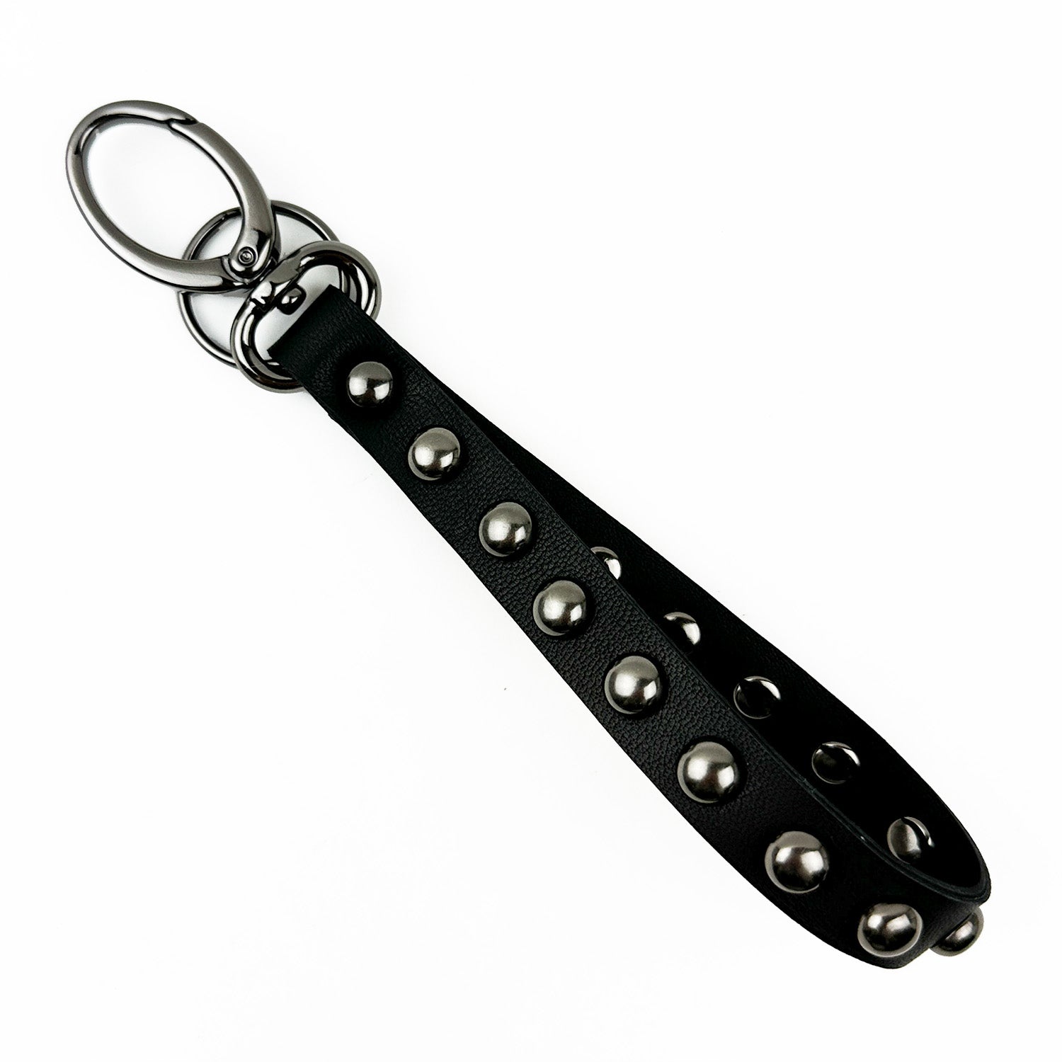 The KEY RING - BLACK STUDDED by evokewomen is a stylish black leather keychain adorned with metal studs and a silver keyring, featuring an edgy strap that enhances your everyday essentials with a touch of flair.