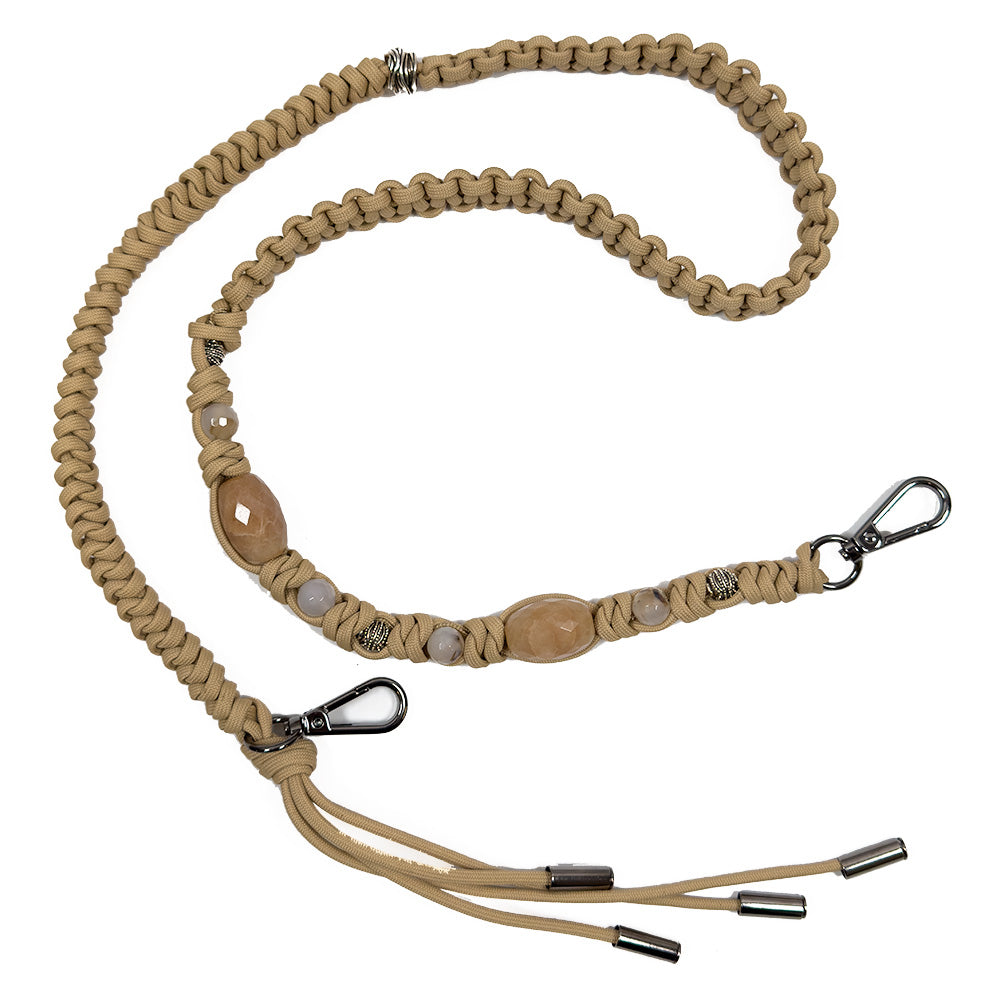 The KNOTTED SHOULDER STRAP - CAMEL by evokewomen is crafted from a tan braided cord, featuring antique silver metal beads and decorative agate beads in the middle, and finished with metal clips on both ends.
