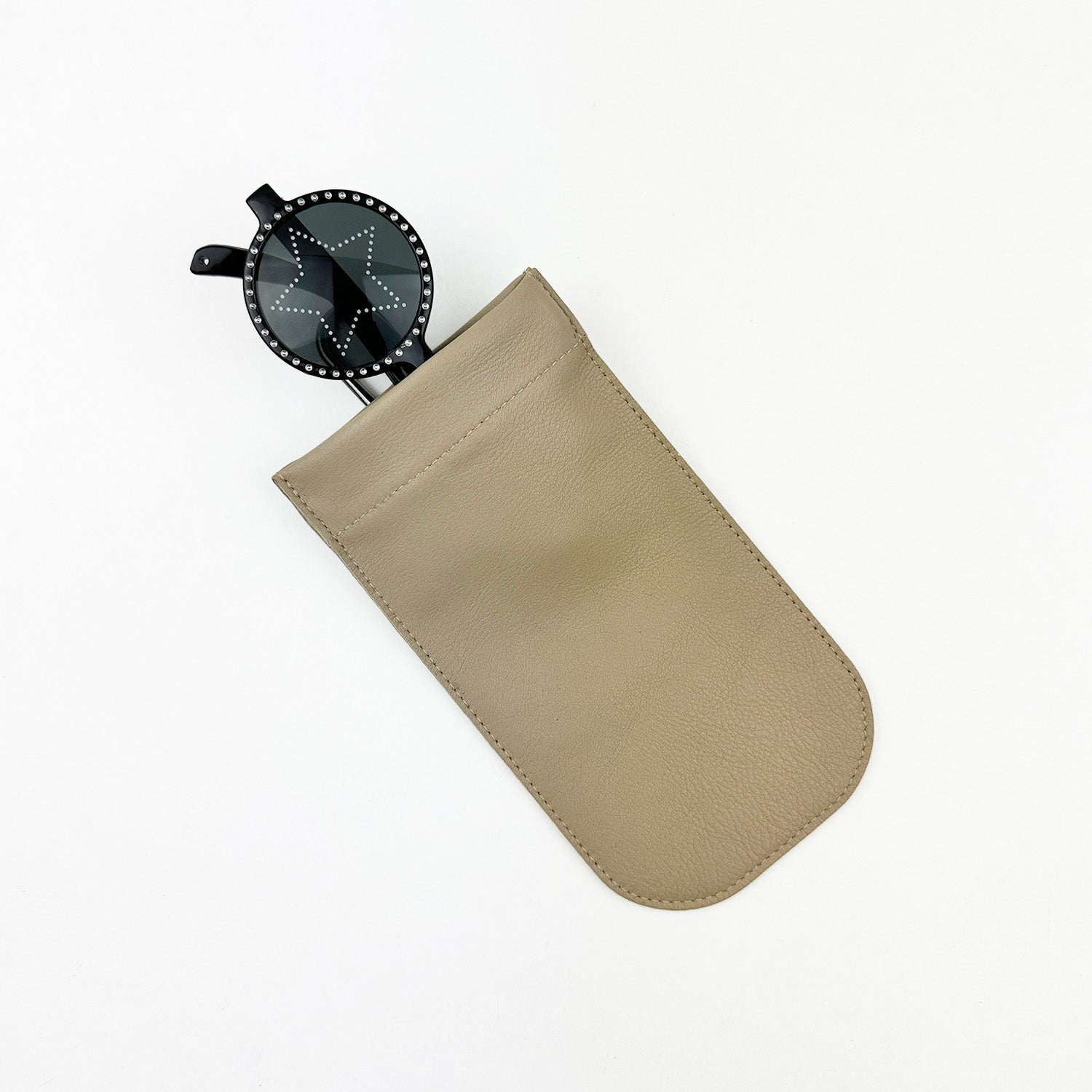 Black star-patterned circular sunglasses peek from the evokewomen SUN-GLASS POUCH - SAND, showcasing a unique design that adds flair while providing eyewear protection against a white background.