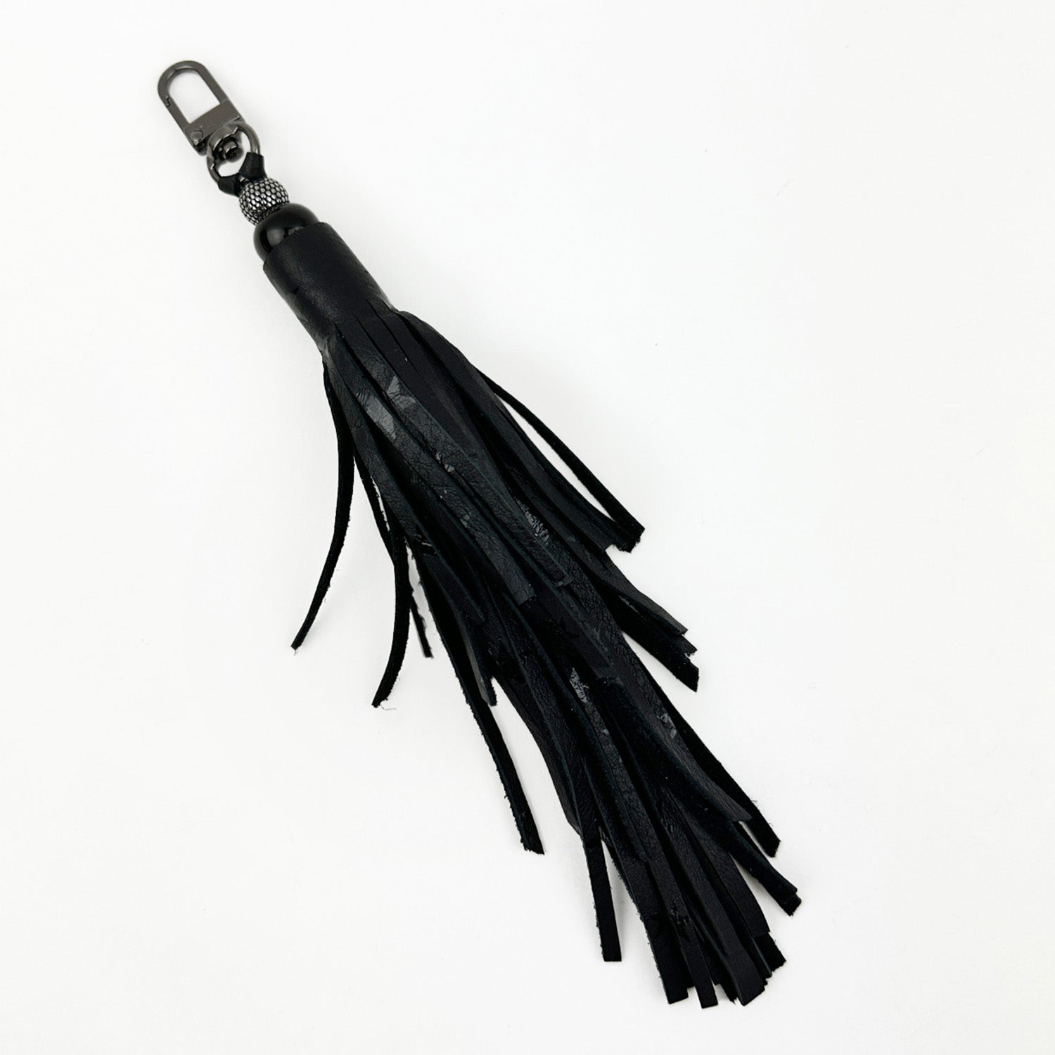 The TASSEL - BLACK STARS by evokewomen is a chic black leather keychain adorned with a tiered tassel and finished with a sleek gunmetal swivel hook at the top.