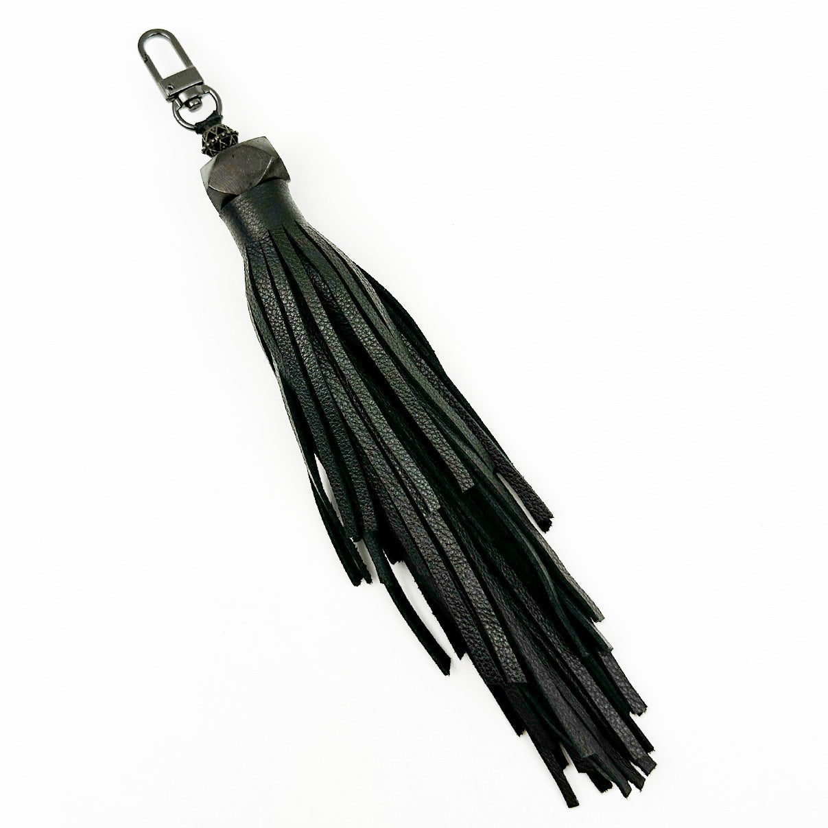 Introducing the evokewomen TASSEL - BLACK LARGE, a chic black leather keychain adorned with fringes and a sleek gunmetal clip, making it an ideal accessory.