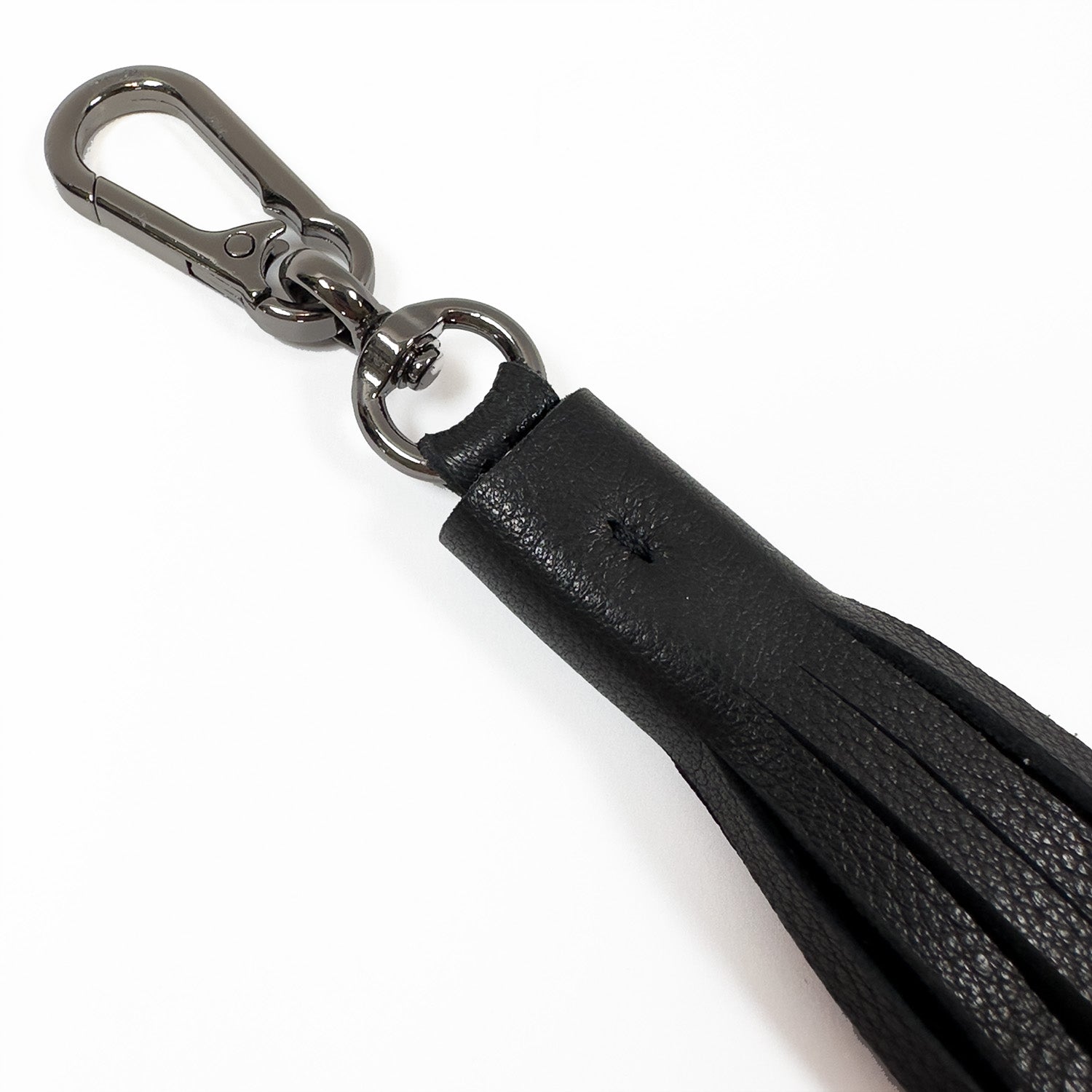 Product Description: The TASSEL XXL - black by evokewomen is a sleek black leather keychain featuring an oversized tassel and a striking metal clasp, showcased on a white background.